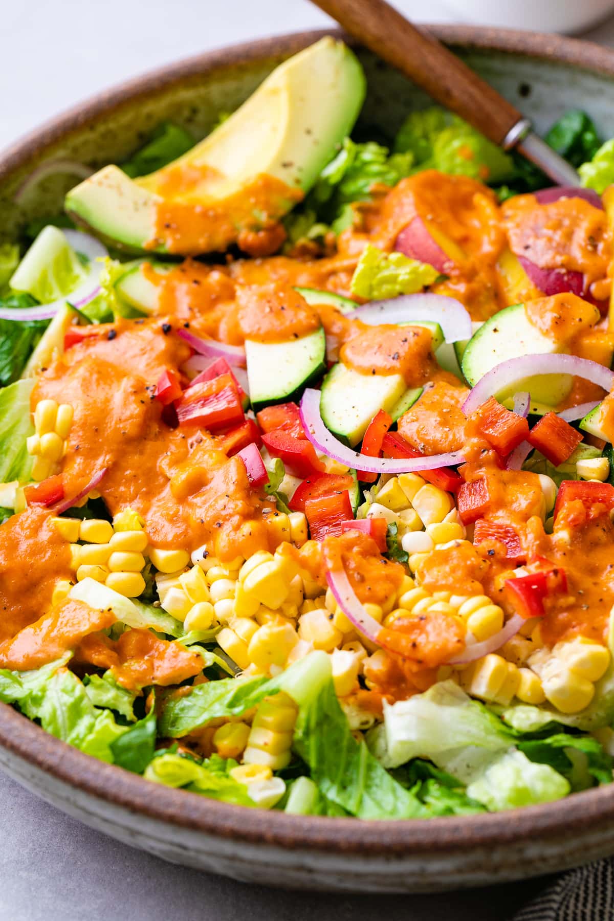 up close, side angle view of healthy farmer's market salad with sun-dried tomato vinaigrette in a bowl.