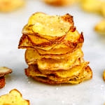 head on view of homemade baked potato chips stacked on top of each other.