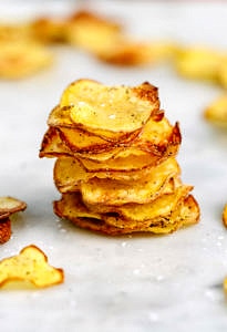 head on view of homemade baked potato chips stacked on top of each other.