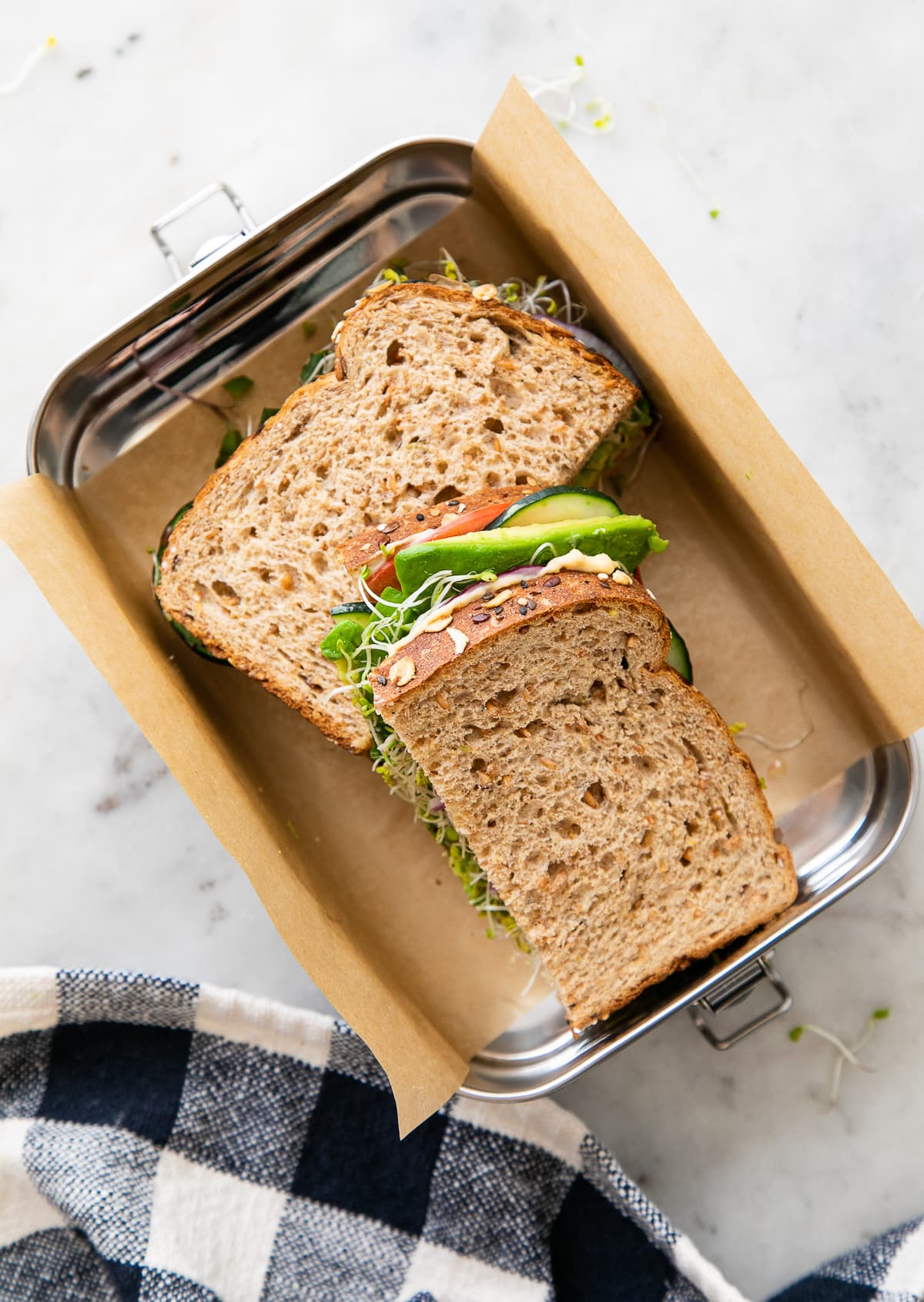 top down view of hummus veggie sandwich sliced in half in travel container.