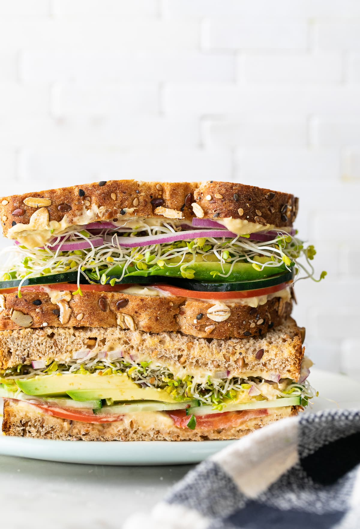 head on view of healthy hummus veggie sandwich sliced in half and stacked.