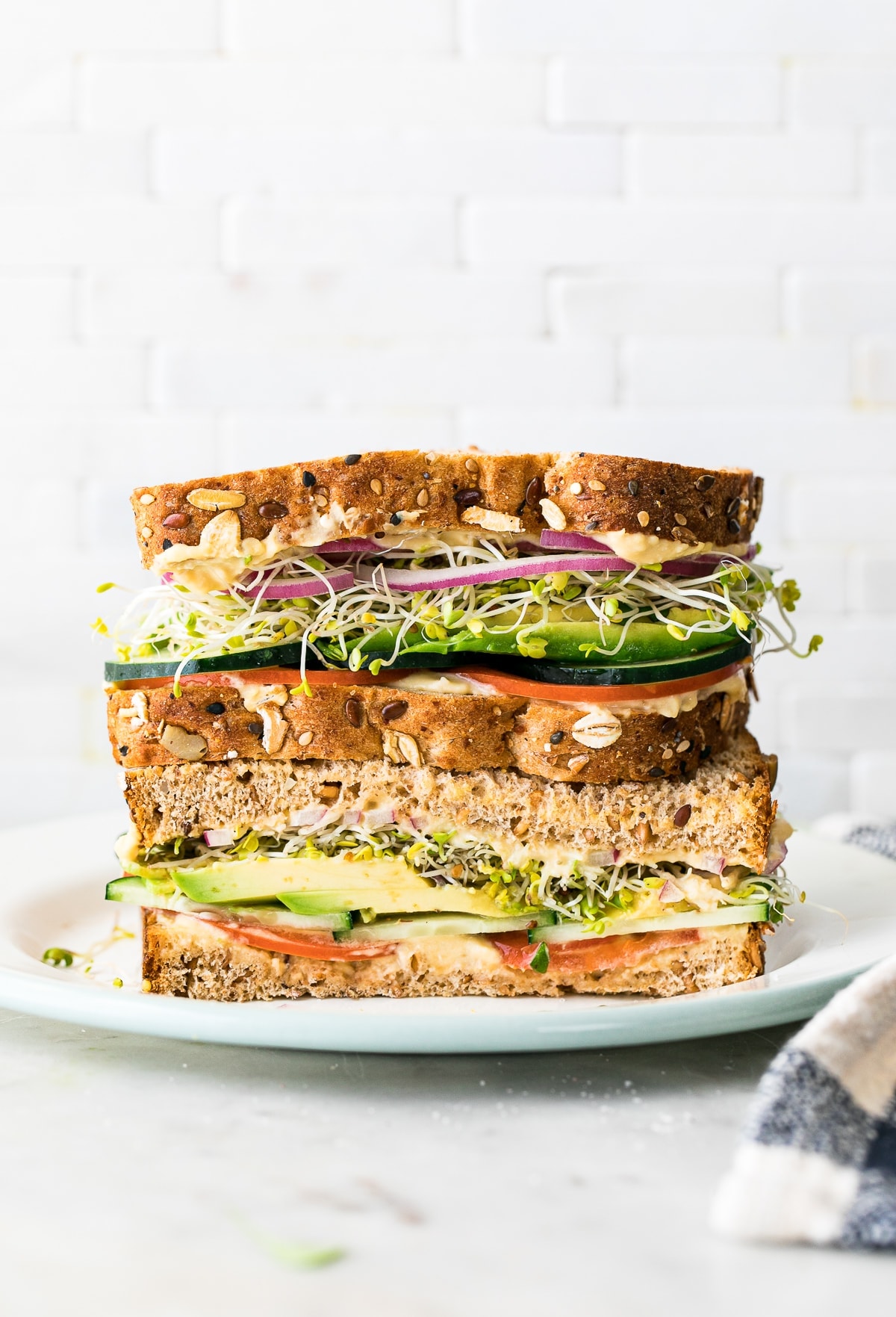 head on view of healthy hummus veggie sandwich sliced in half and stacked.