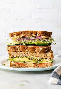 head on view of healthy hummus veggie sandwich sliced in half and stacked.