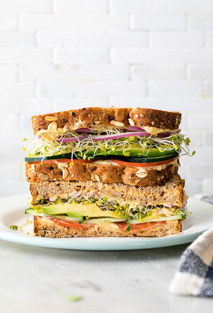 head on view of healthy hummus veggie sandwich sliced in half and stacked.