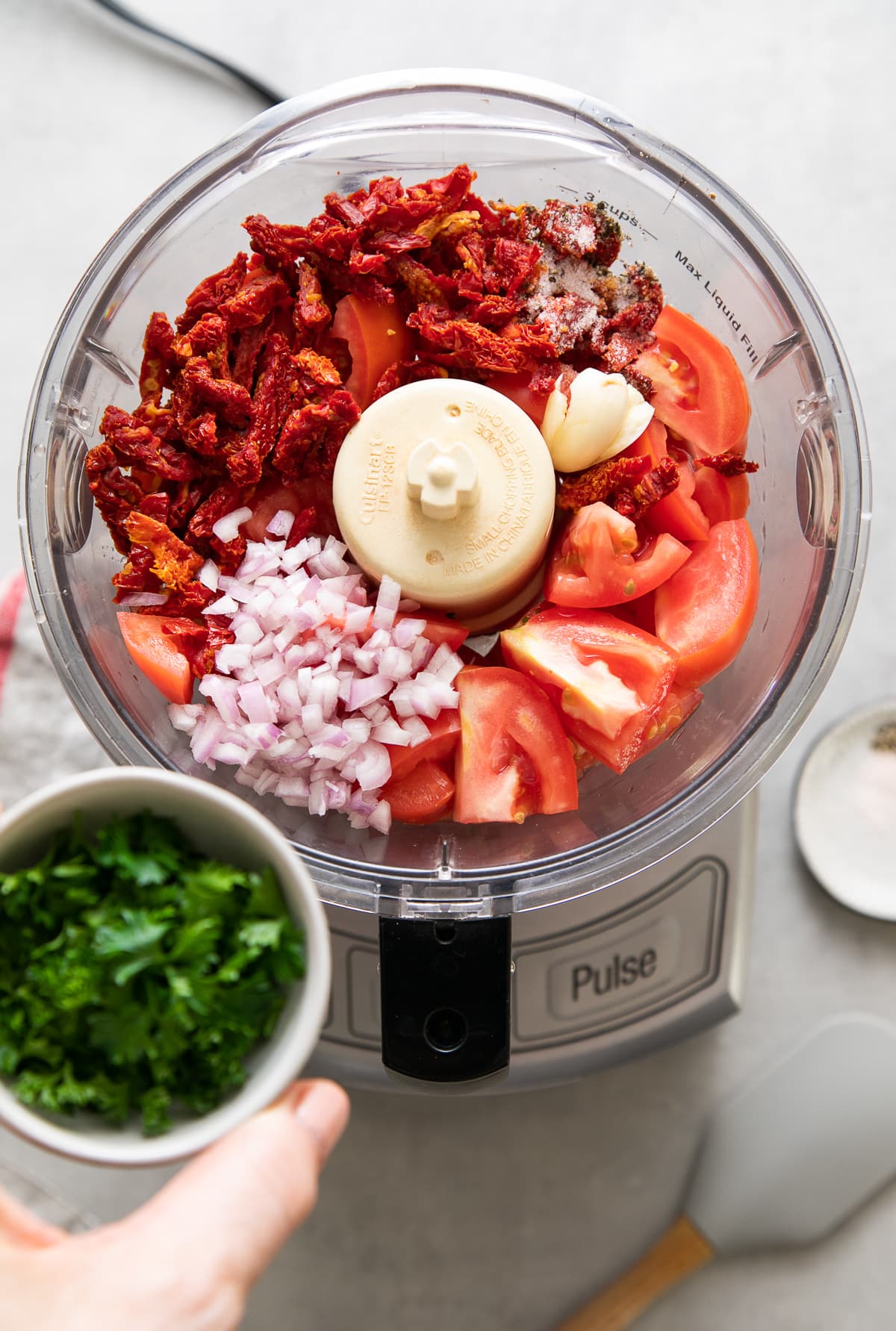 top down view of ingredients for raw marinara sauce added to food processor.