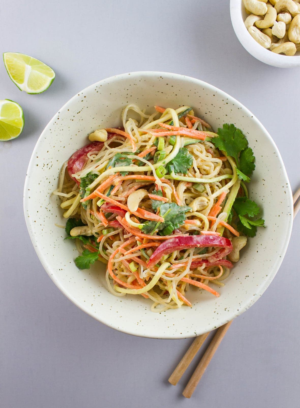 top down view of raw pad thai in a bowl with items surrouding.