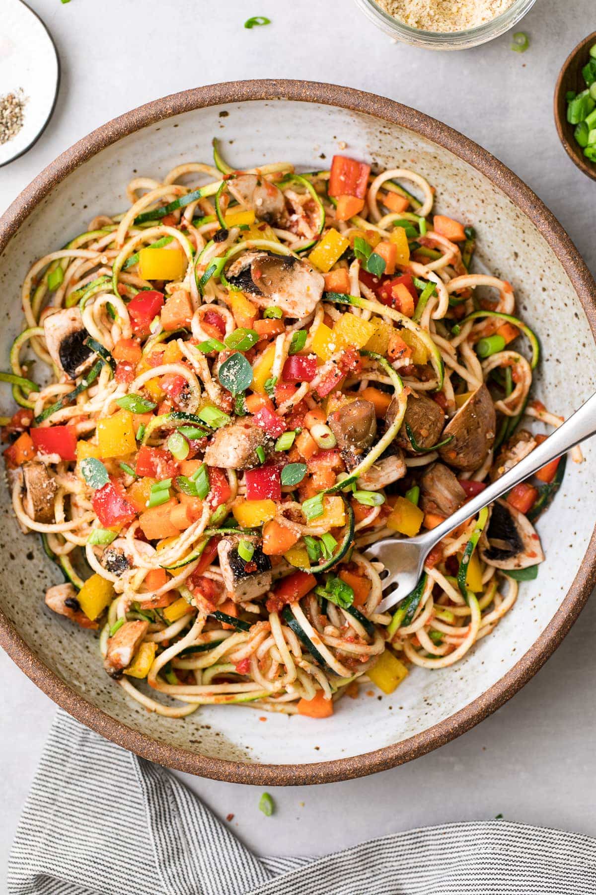 top down view of plated raw vegetable pasta with items surrounding.