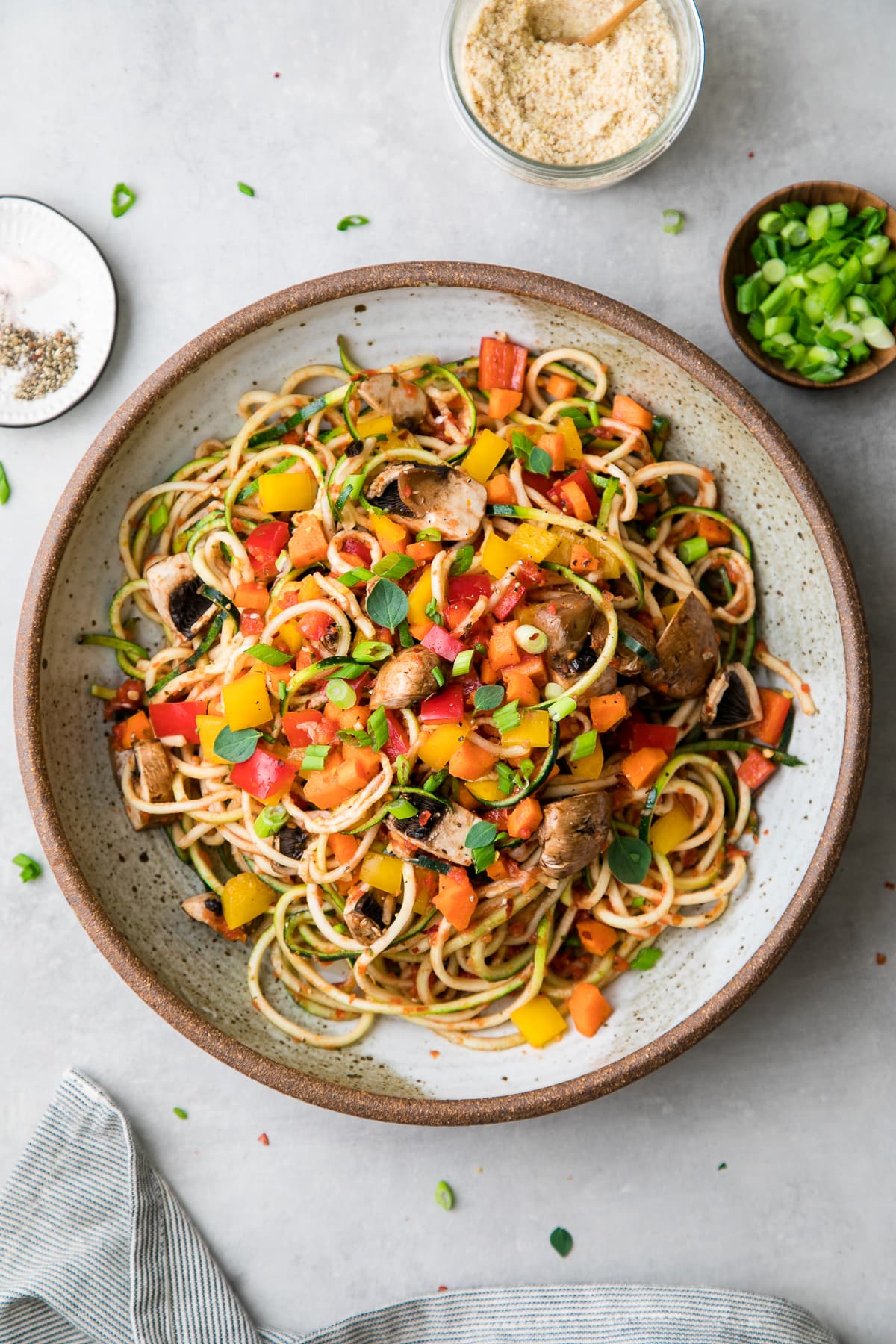 top down view of plated raw vegetable pasta with items surrounding.