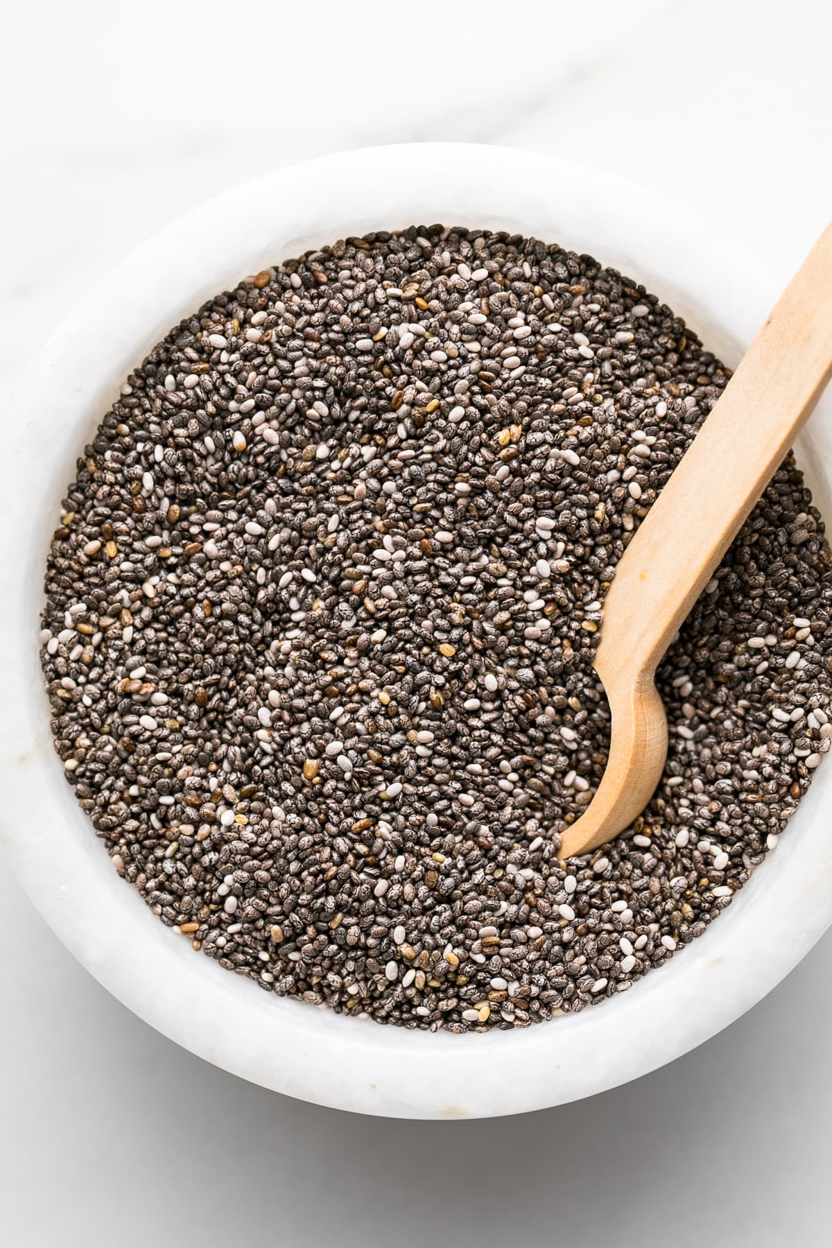 side angle view of chia seeds in a bowl with wooden spoon.