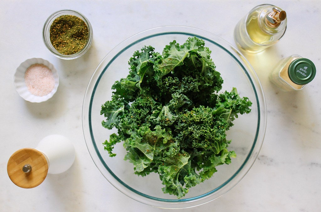 top down view showing the process of making crispy baked kale chips.