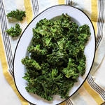 crispy baked kale chips on an oval white plate with black rim