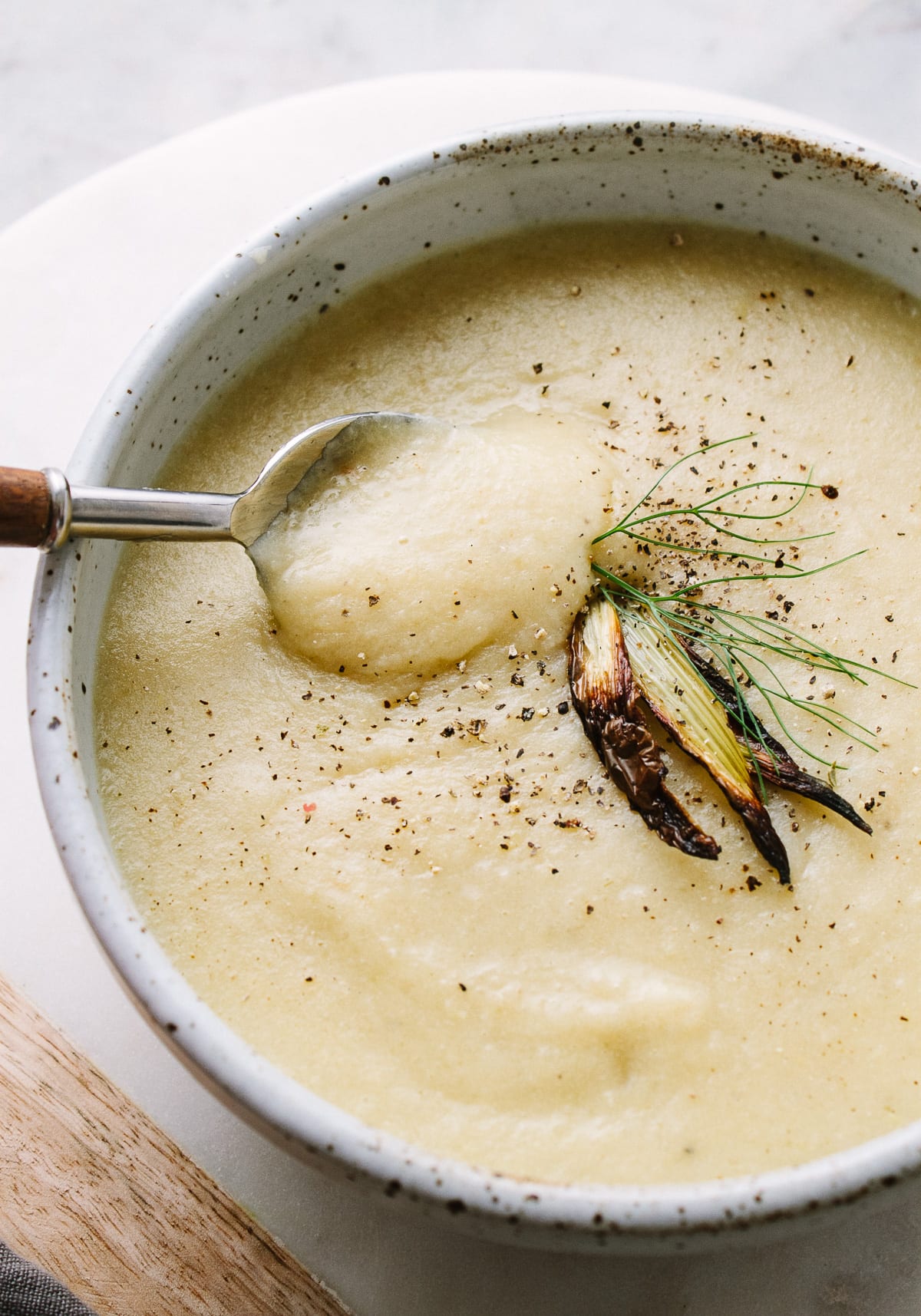 top down view of a bowl full of roasted fennel and potato soup with spoon.