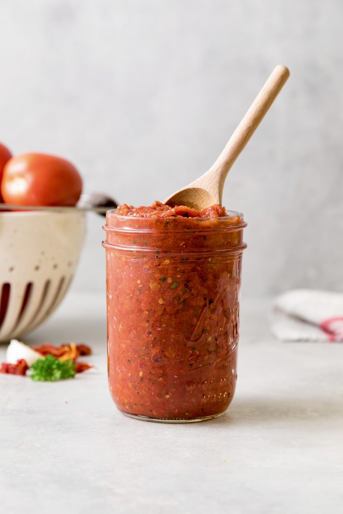 head on view of mason jar filled with raw marinara sauce with wooden spoon.