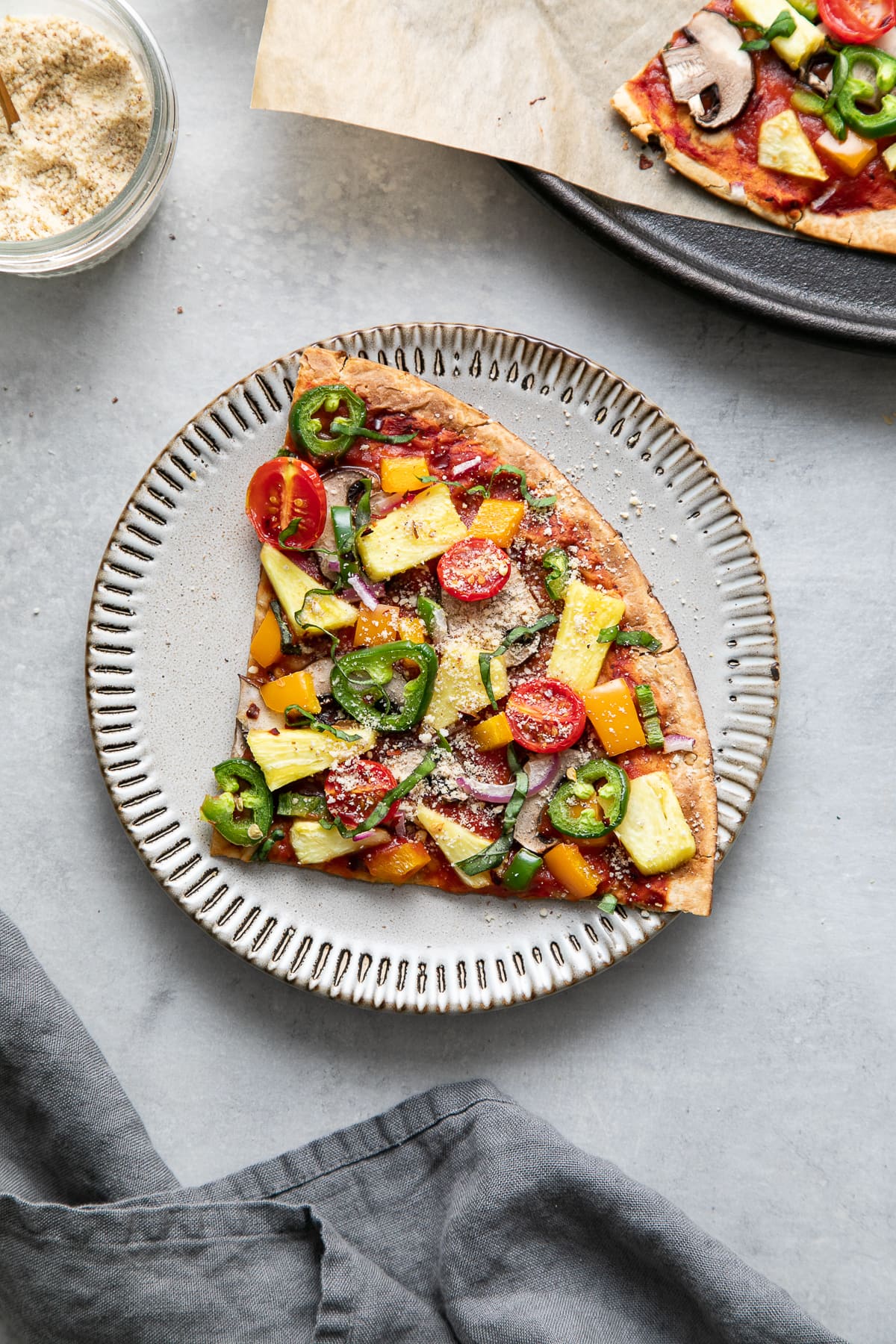 top down view of slice of pineapple veggie lovers pizza on a small plate.