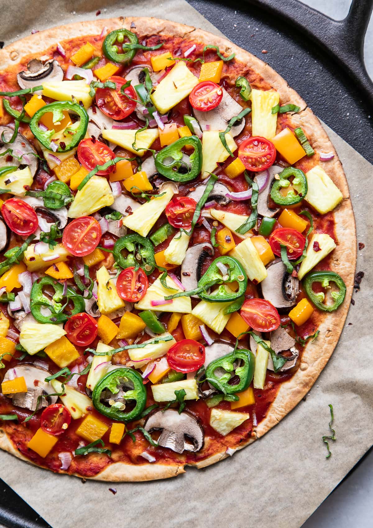 top down view of freshly baked pineapple veggie lovers pizza on a cast iron pizza pan.