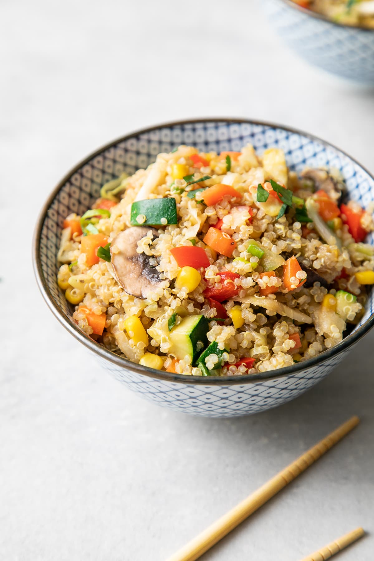 side angle view of blue and white bowl with vegetable quinoa fried rice.