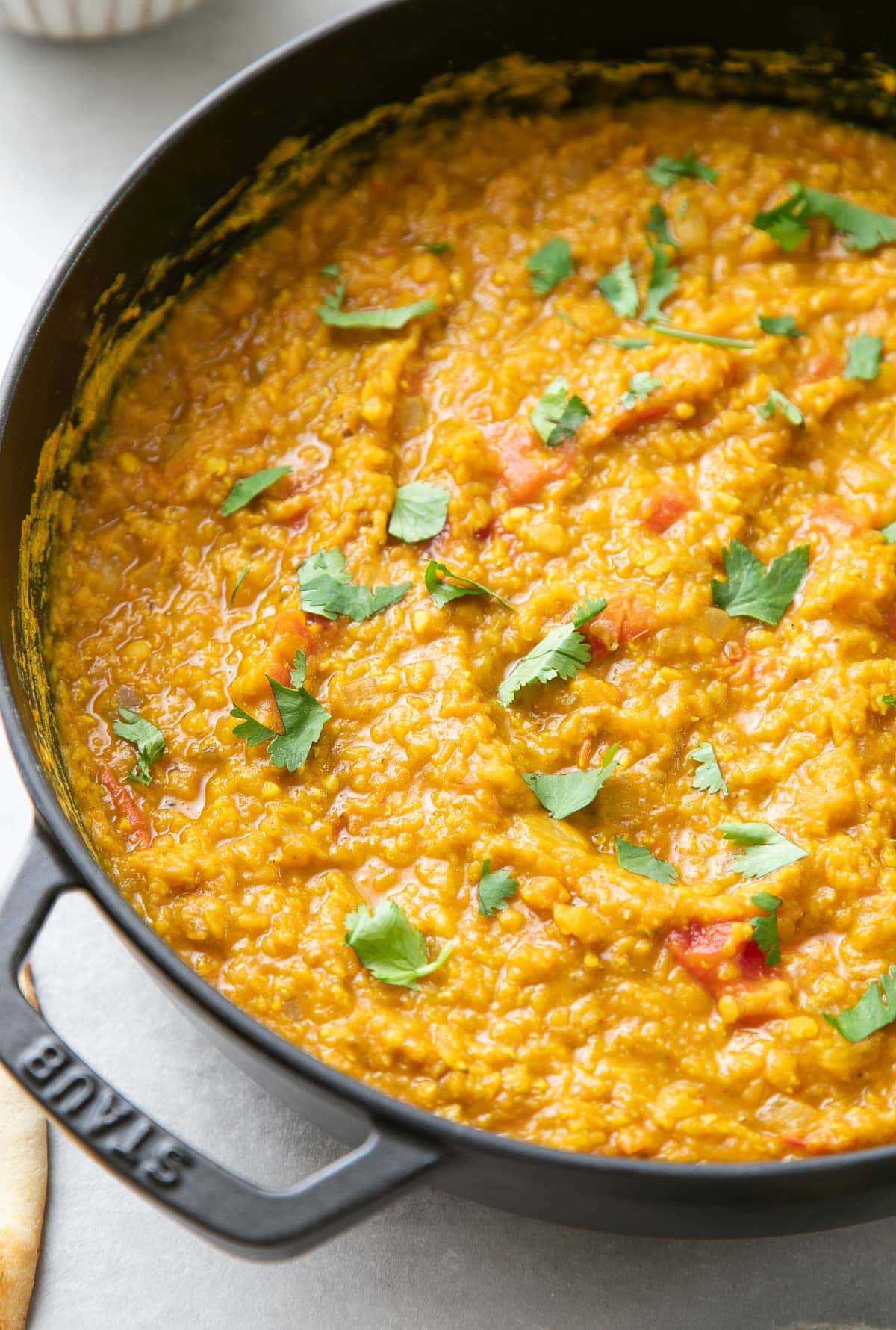 side angle view of freshly make red lentil dal in a cast iron pot.