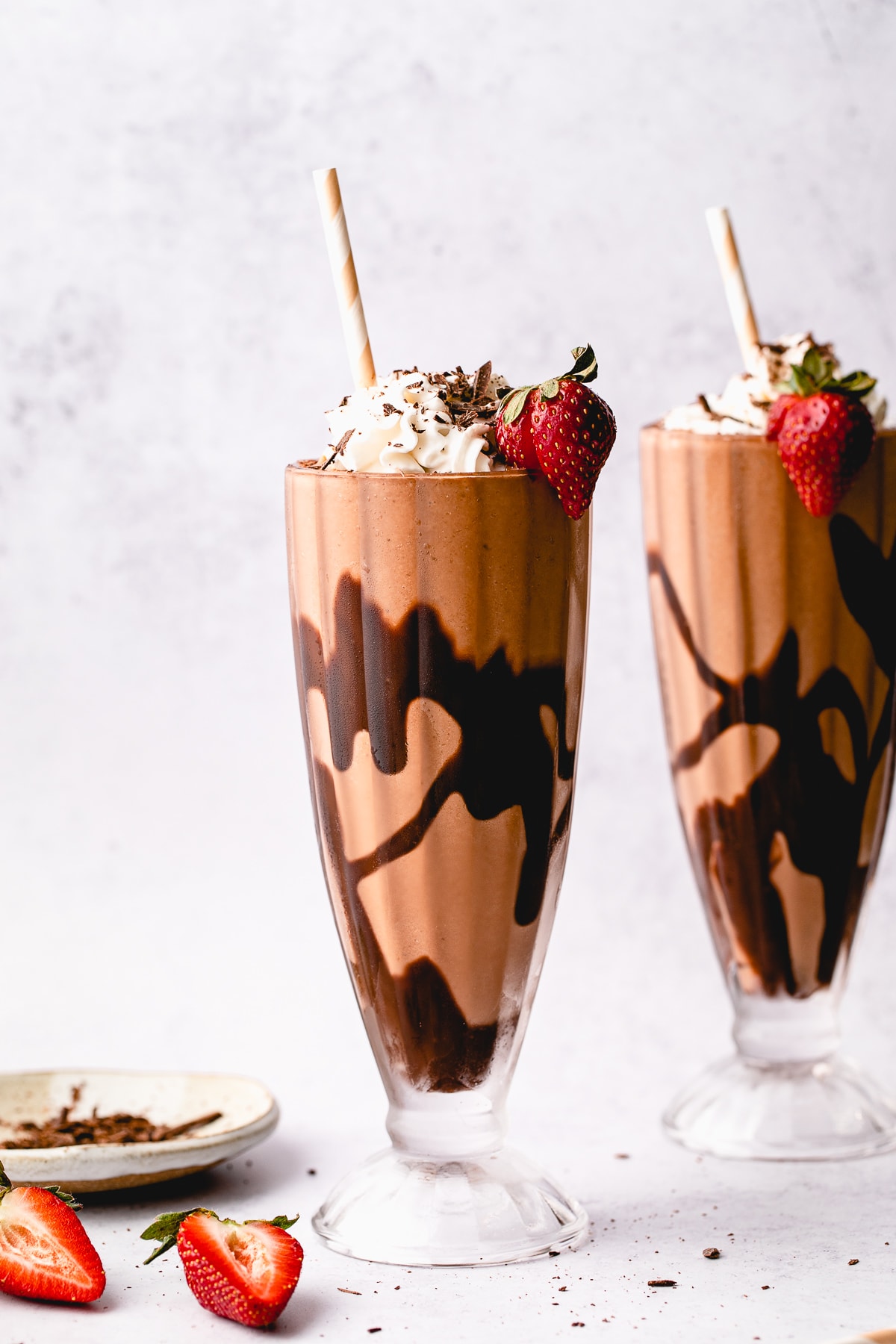 head on view of chocolate vegan milkshake in a frosted glass with straw.