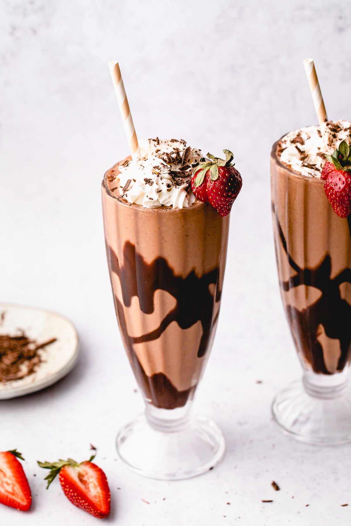 head on view of chocolate vegan milkshake in a frosted glass with straw.