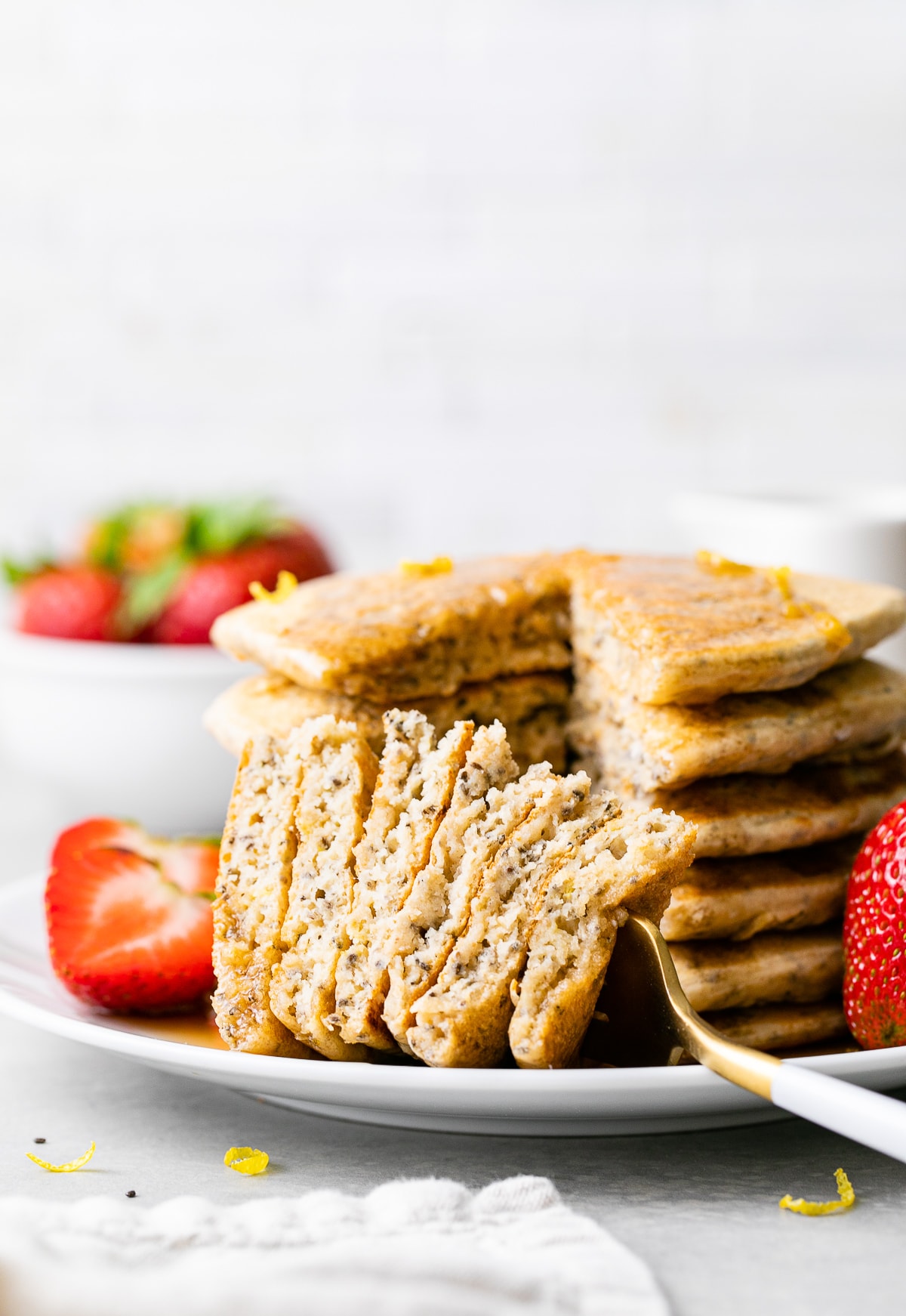 head on view of stack of lemon chia seed pancakes with sliced removed on a fork.