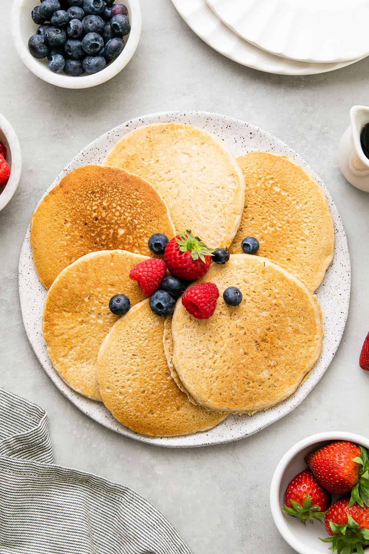 top down view of the best classic vegan pancakes on a serving dish with items surrounding.