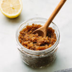 side angle view of edible sugar body scrub in a glass mason jar with wooden spoon.