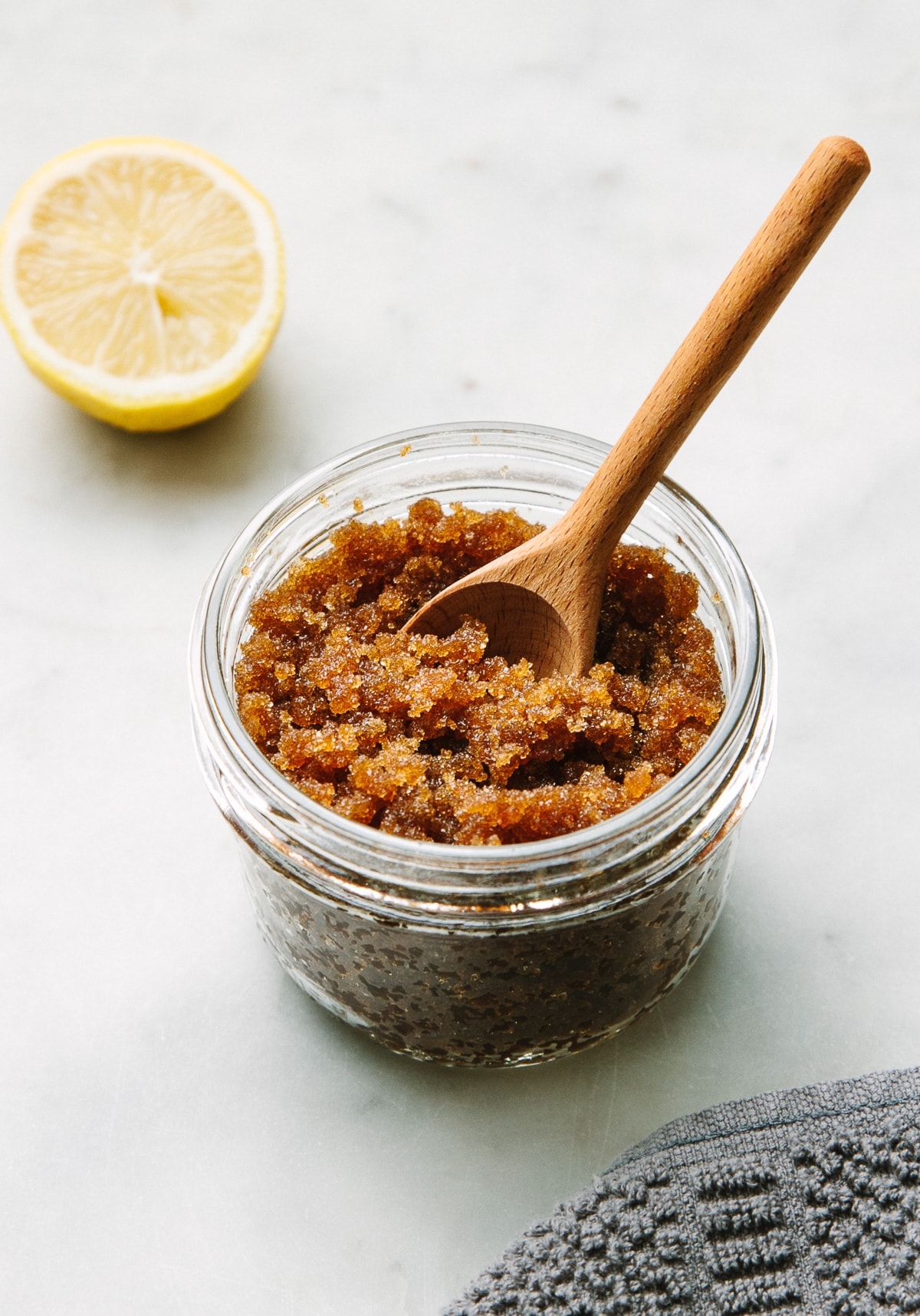 side angle view of edible sugar body scrub in a glass mason jar with wooden spoon.