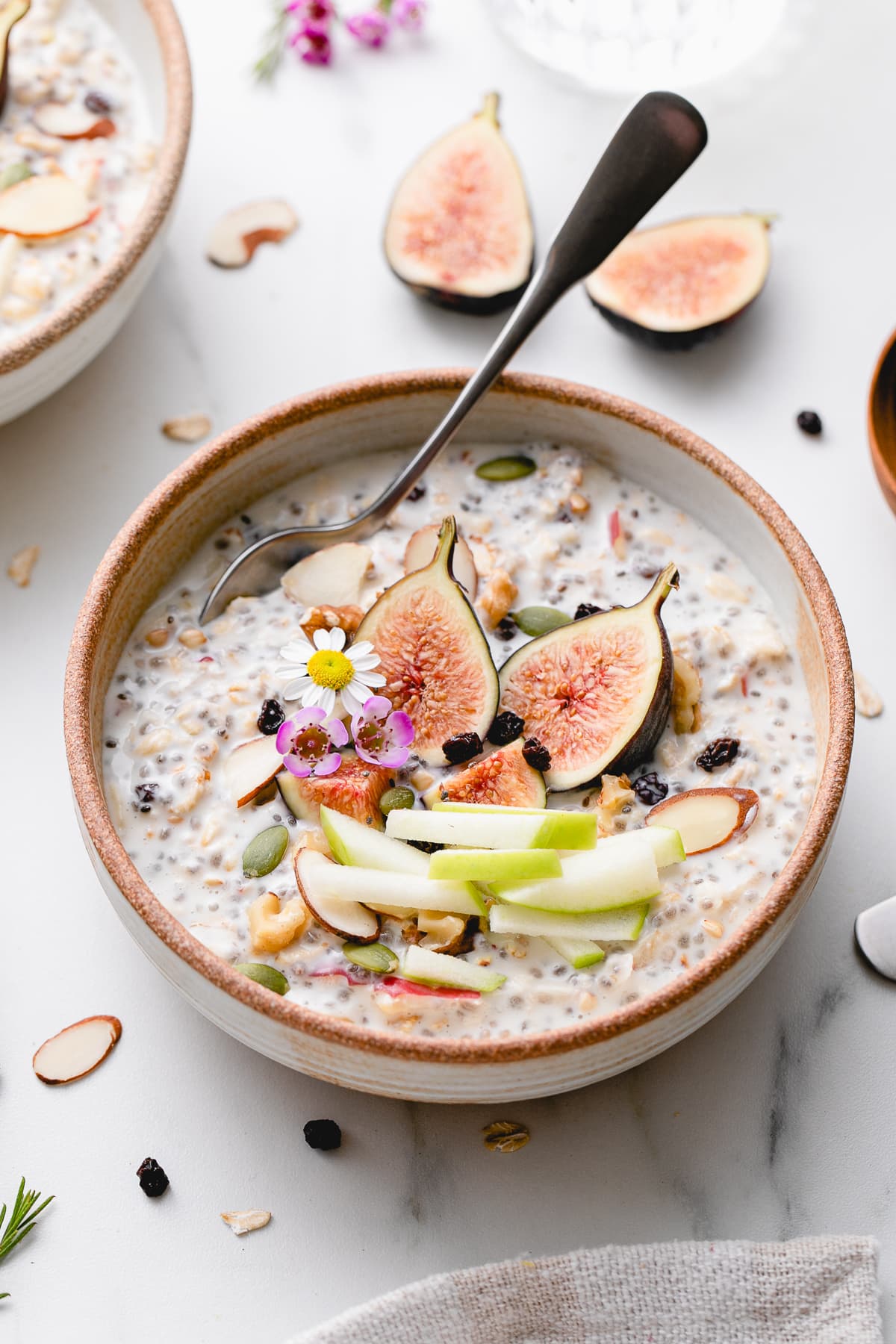 side angle view of bowl of bircher muesli with fruits and nuts with items surrounding.