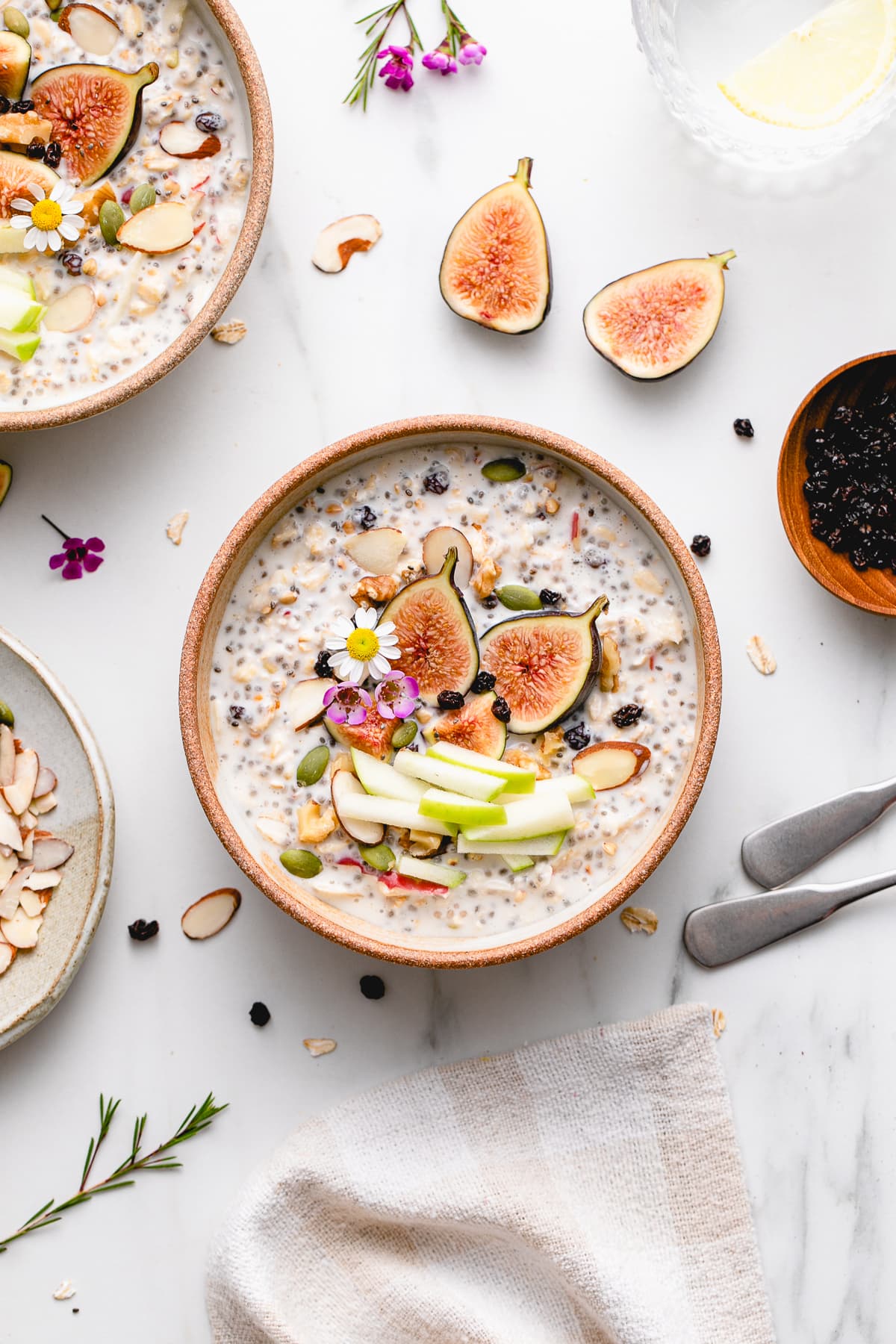 top down view of bowl of bircher muesli with fruits and nuts with items surrounding.