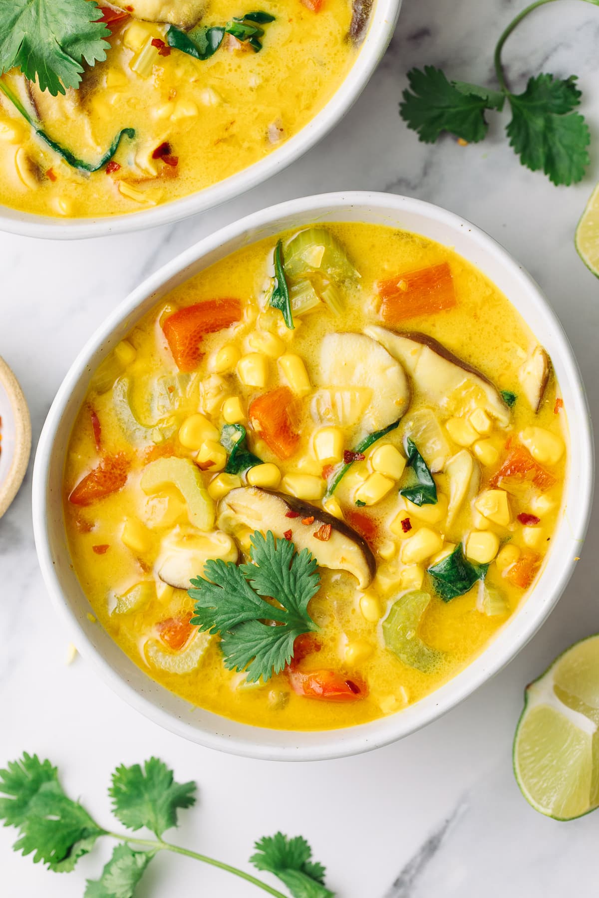 top down view of plated thai coconut curry corn soup with items surrounding.