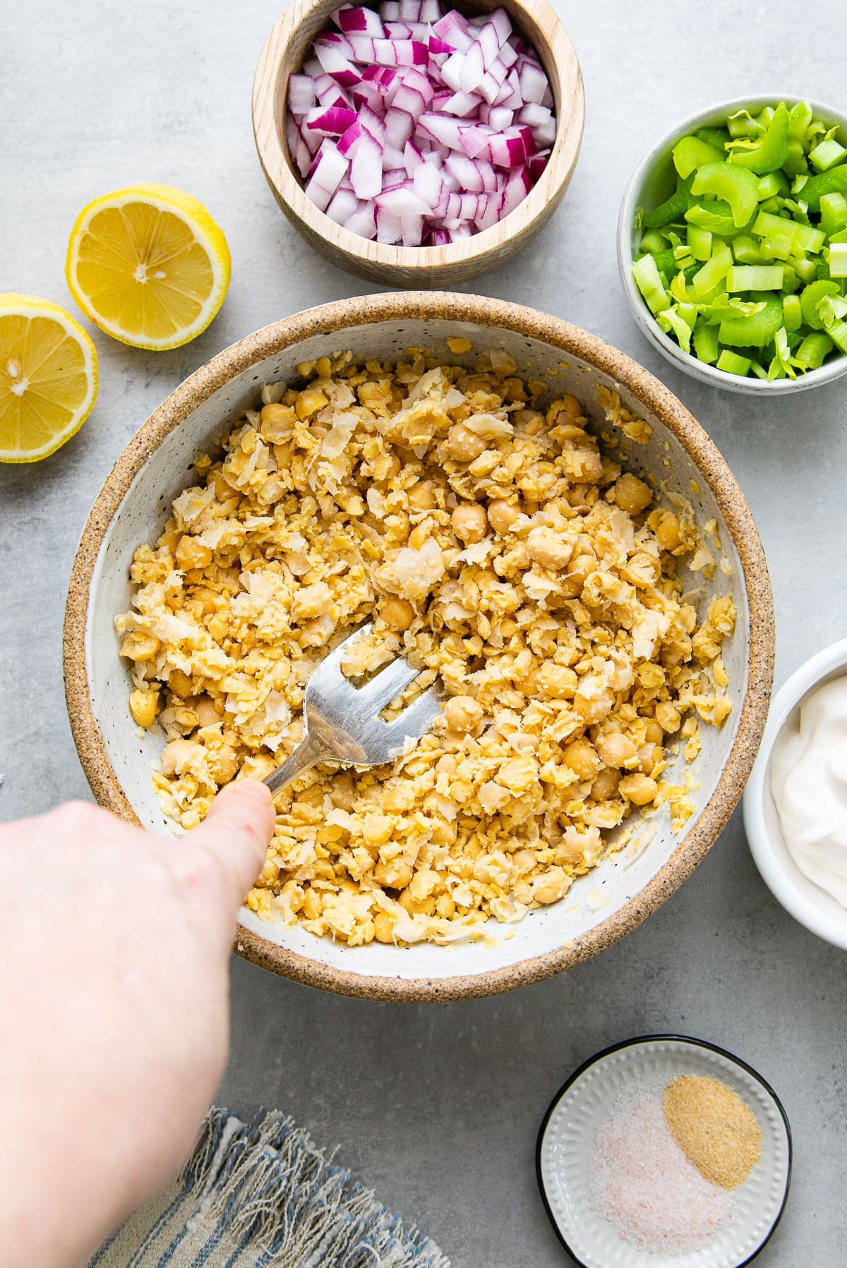 top down view showing the process of mashing chickpeas with items surrounding.