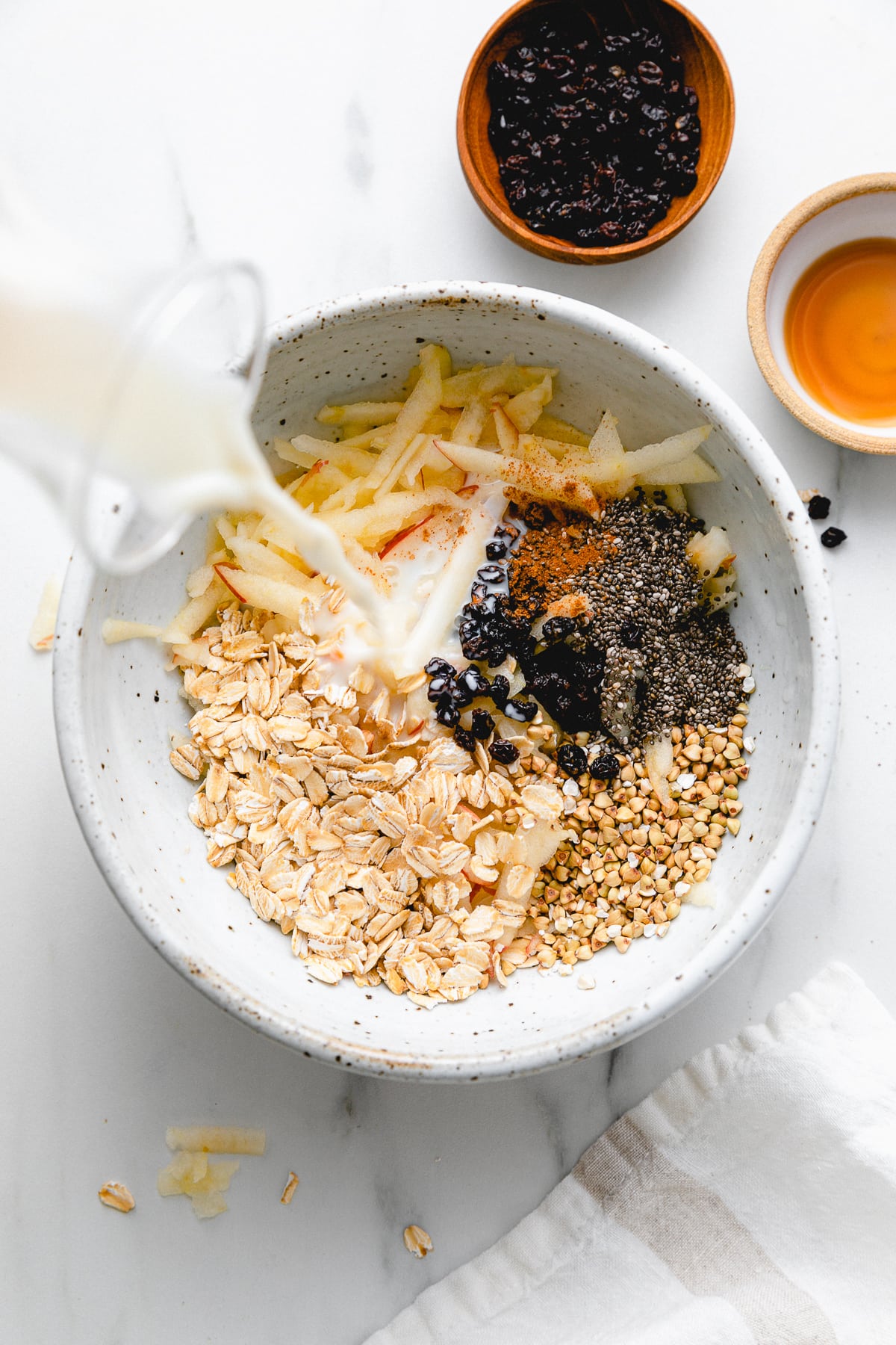 top down view showing the process of making healthy bircher muesli in a bowl.