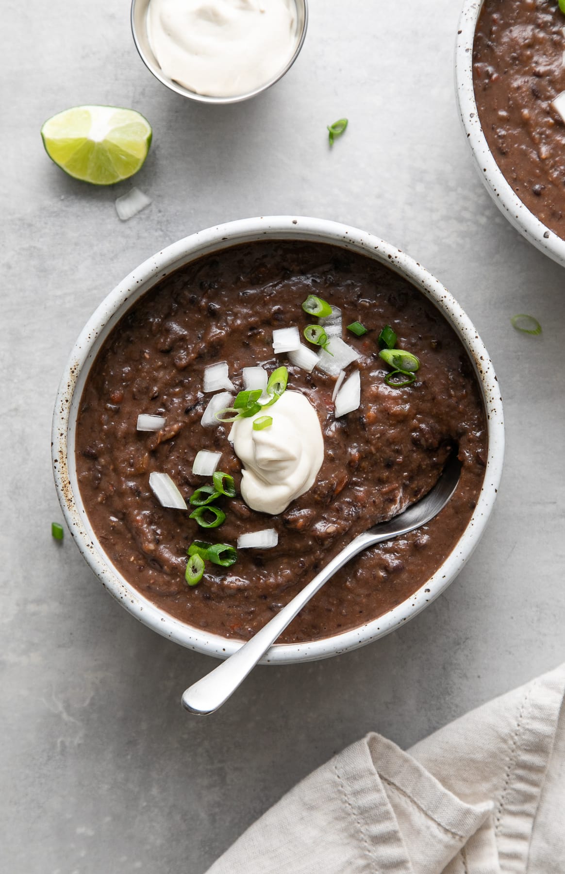 top down view of a bowl full of healthy cuban black bean soup with items surrounding.