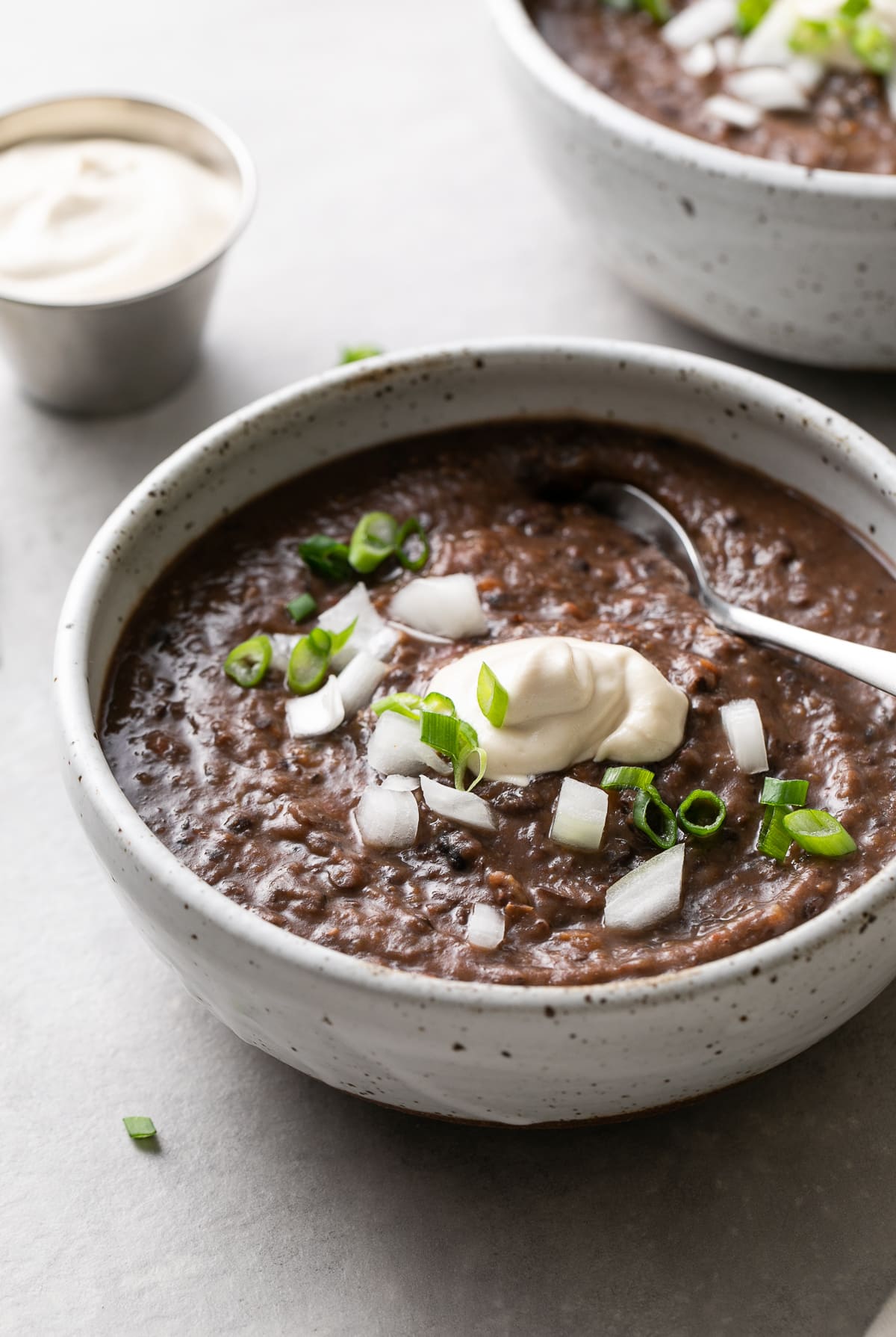 side angle view of a bowl full of healthy cuban black bean soup with items surrounding.