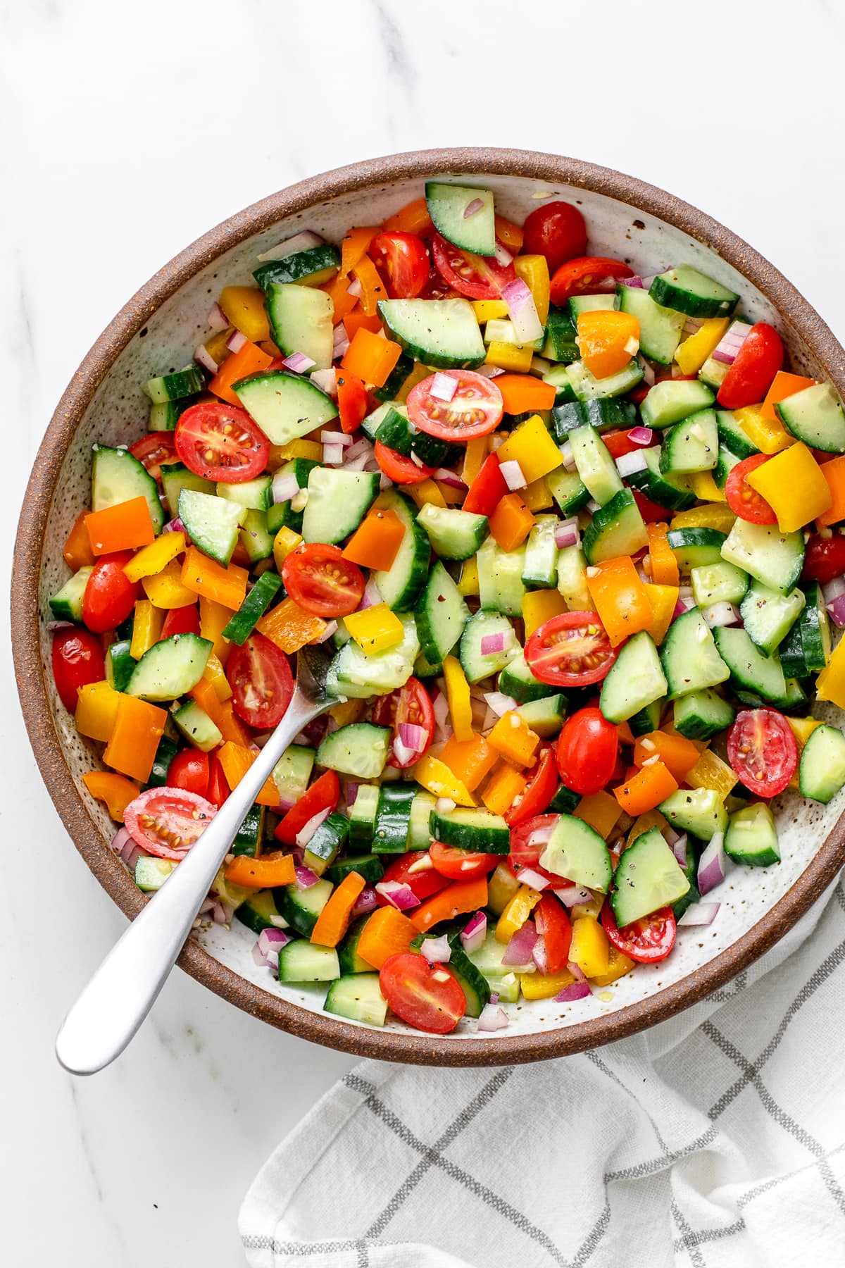 top down view of freshly made vegetable salad in a bowl with serving spoon.