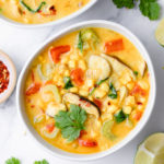 top down view of plated thai coconut curry corn soup with items surrounding.