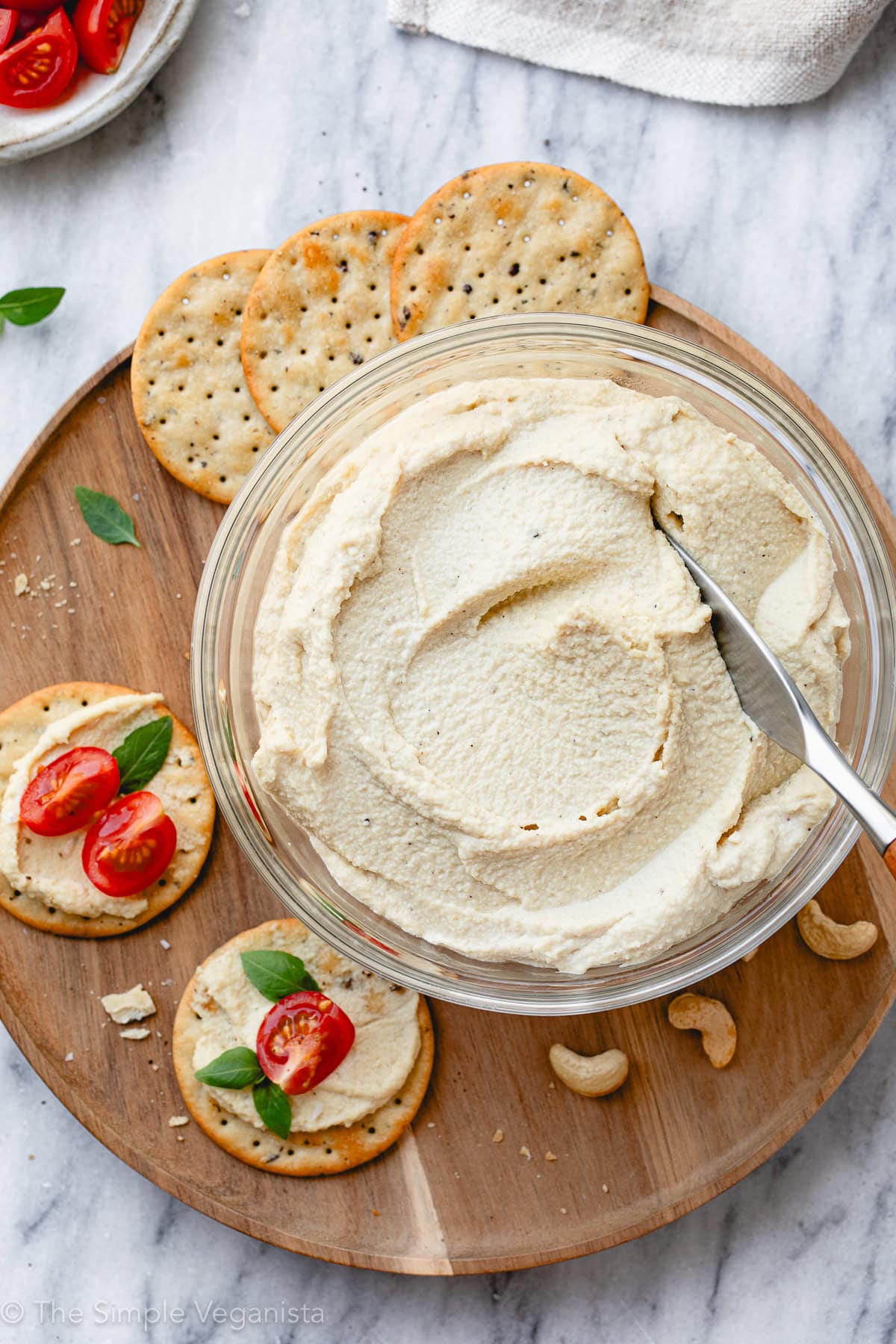 top down view of creamy cashew ricotta in a glass bowl with items surrounding.