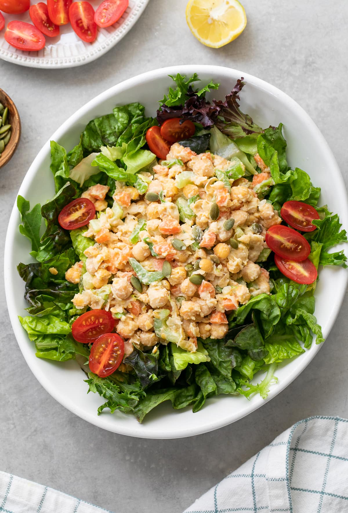 top down view of healthy mashed chickpea salad with leafy greens in white bowl.