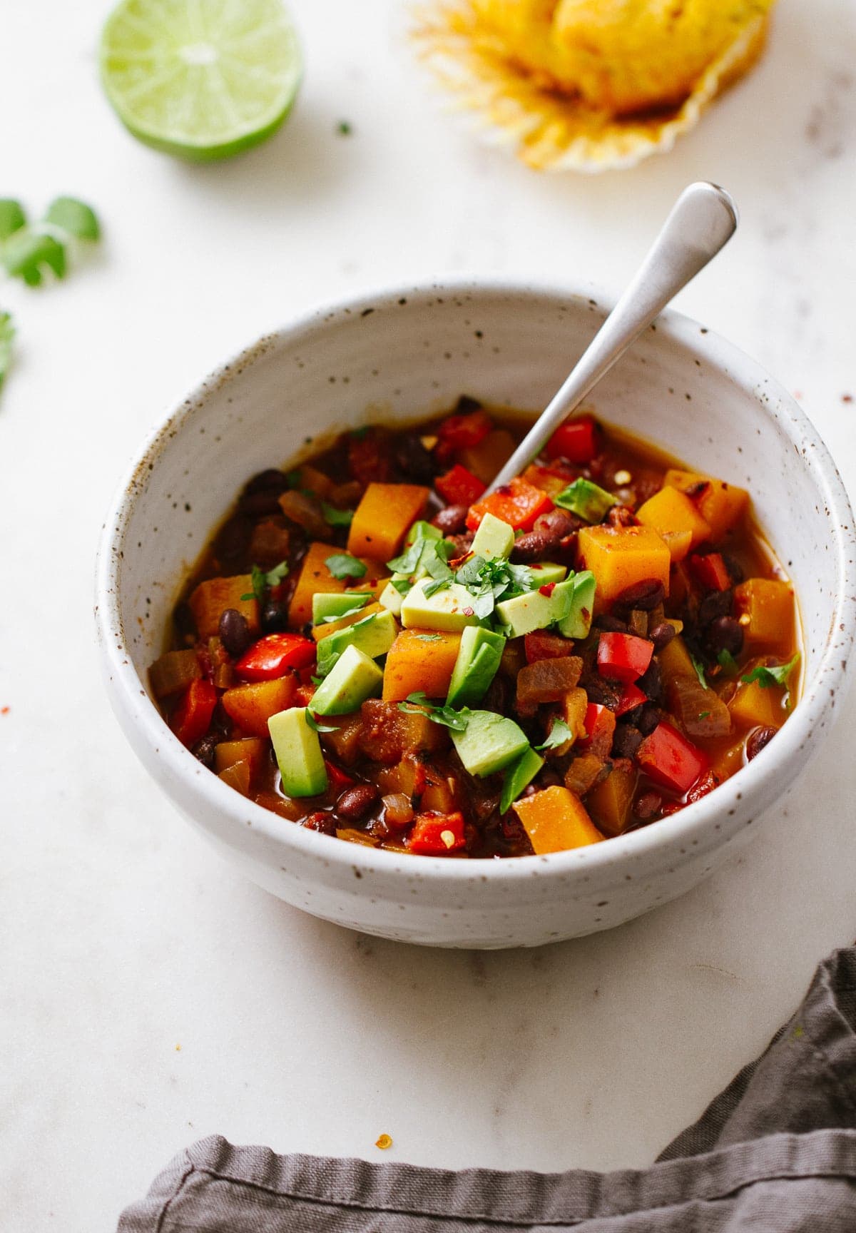 side angle view of black bean and butternut squash chili in a serving bowl with spoon.