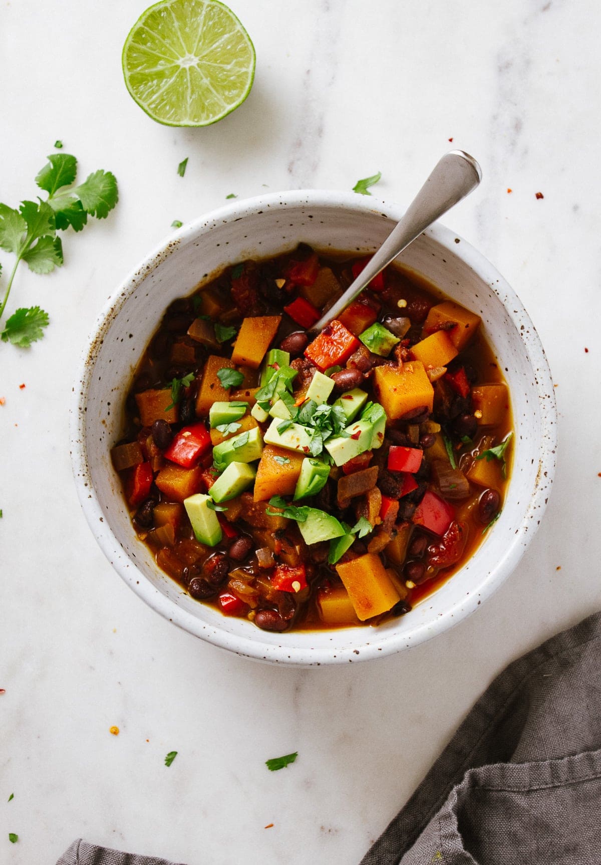 top down view of black bean and butternut squash chili in a serving bowl with spoon.