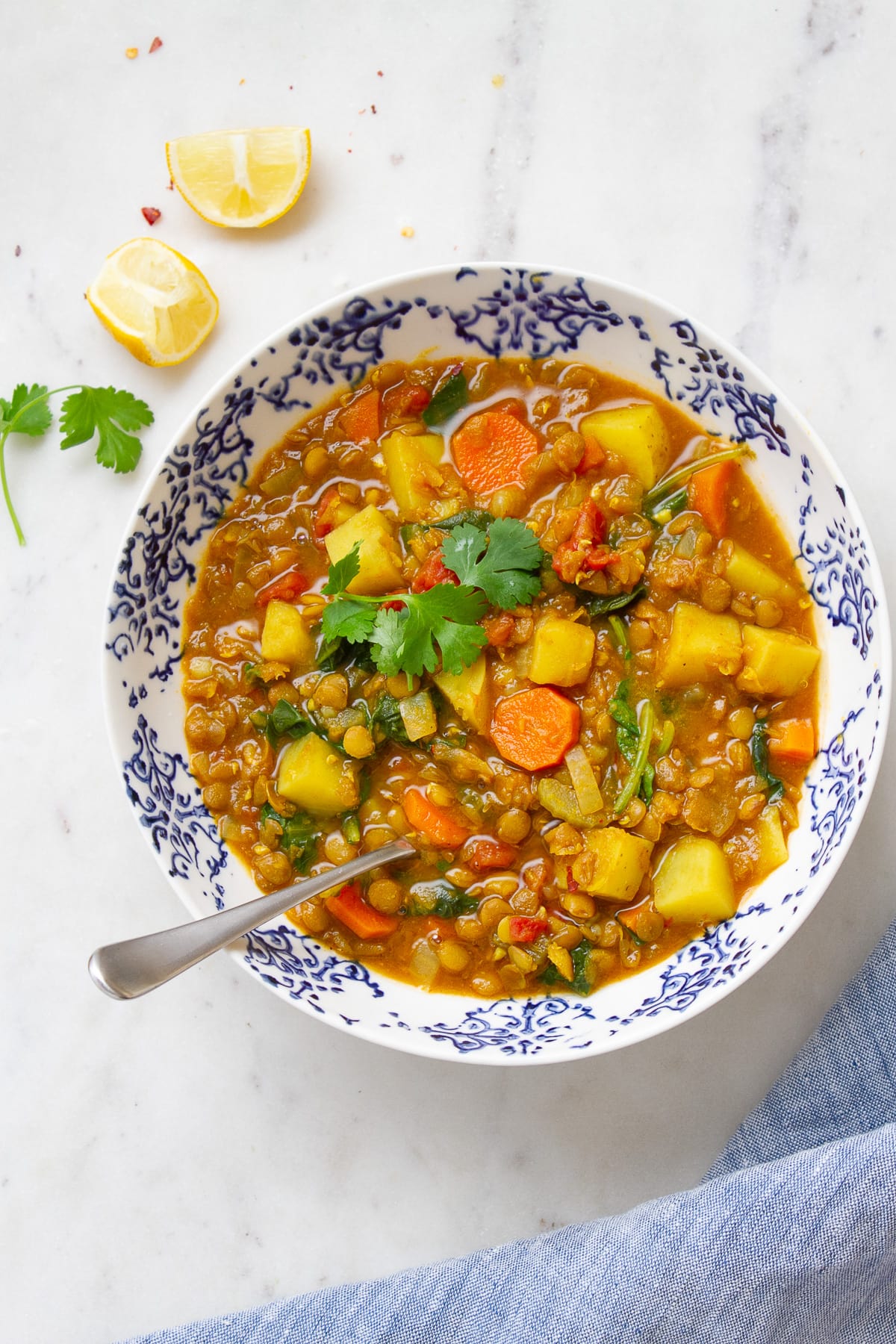 top down view of bowl filled with a serving of hearty curry lentil lentil soup with spinach and potatoes.