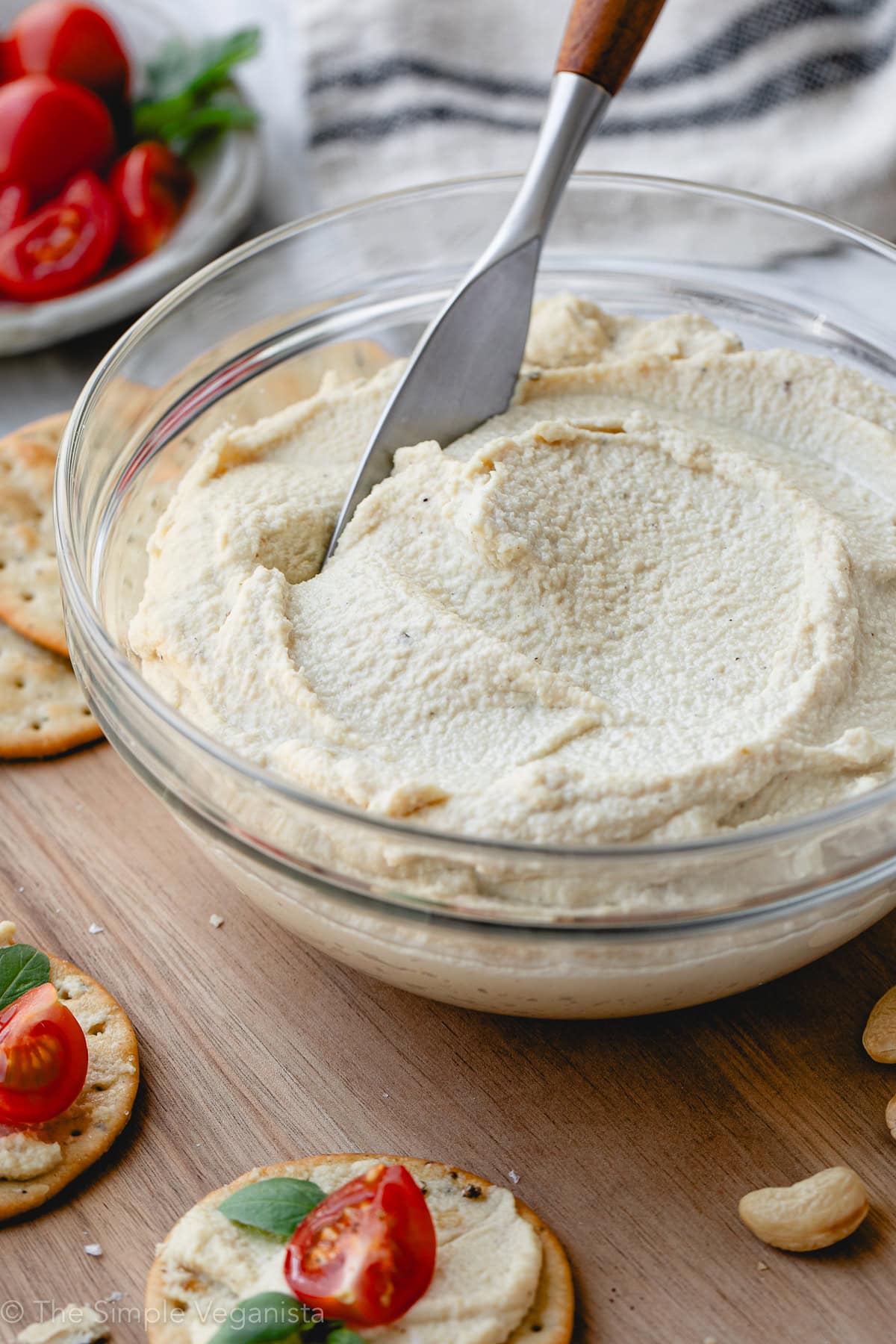 side angle view of creamy cashew ricotta in a glass bowl with items surrounding.