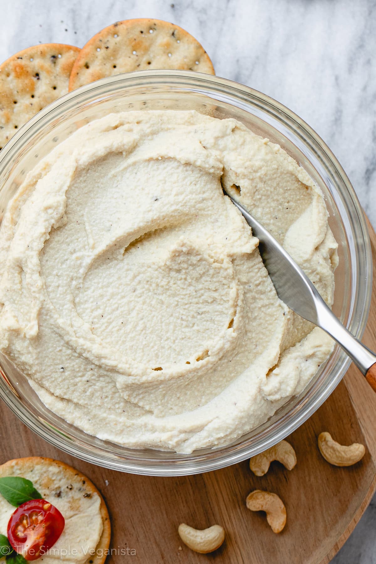 top down view of creamy cashew ricotta in a glass bowl with items surrounding.