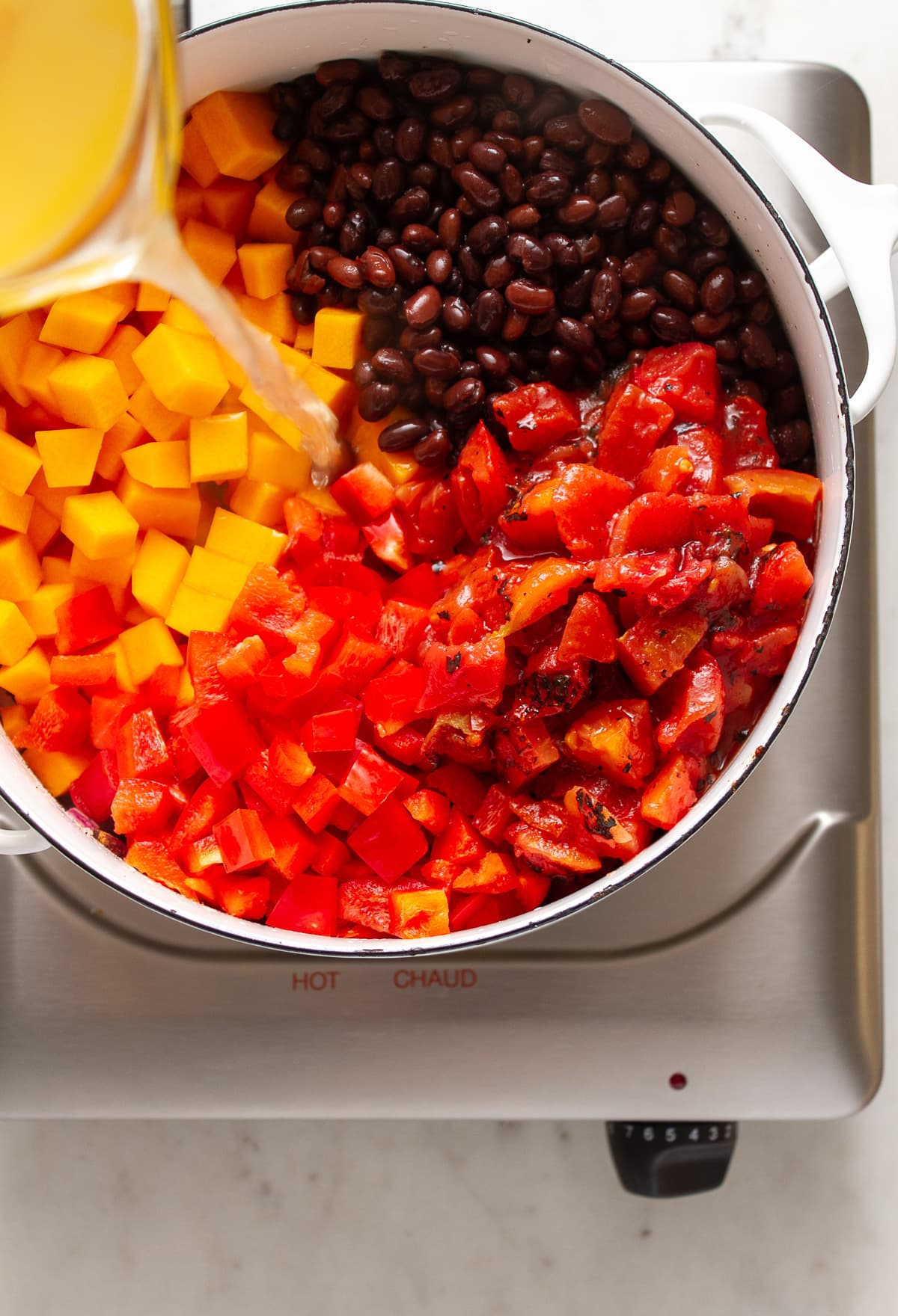 top down view showing the process of making butternut squash chili with black beans on the stovetop.