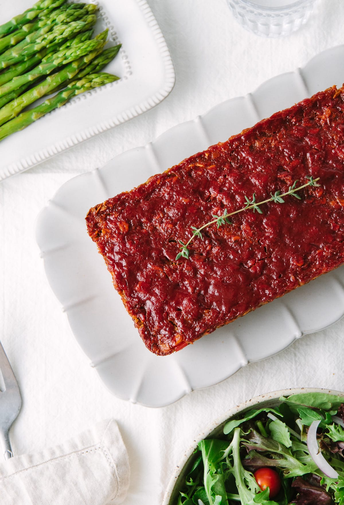 top down view of vegetable lentil loaf on a serving platter surrounded by side dishes.