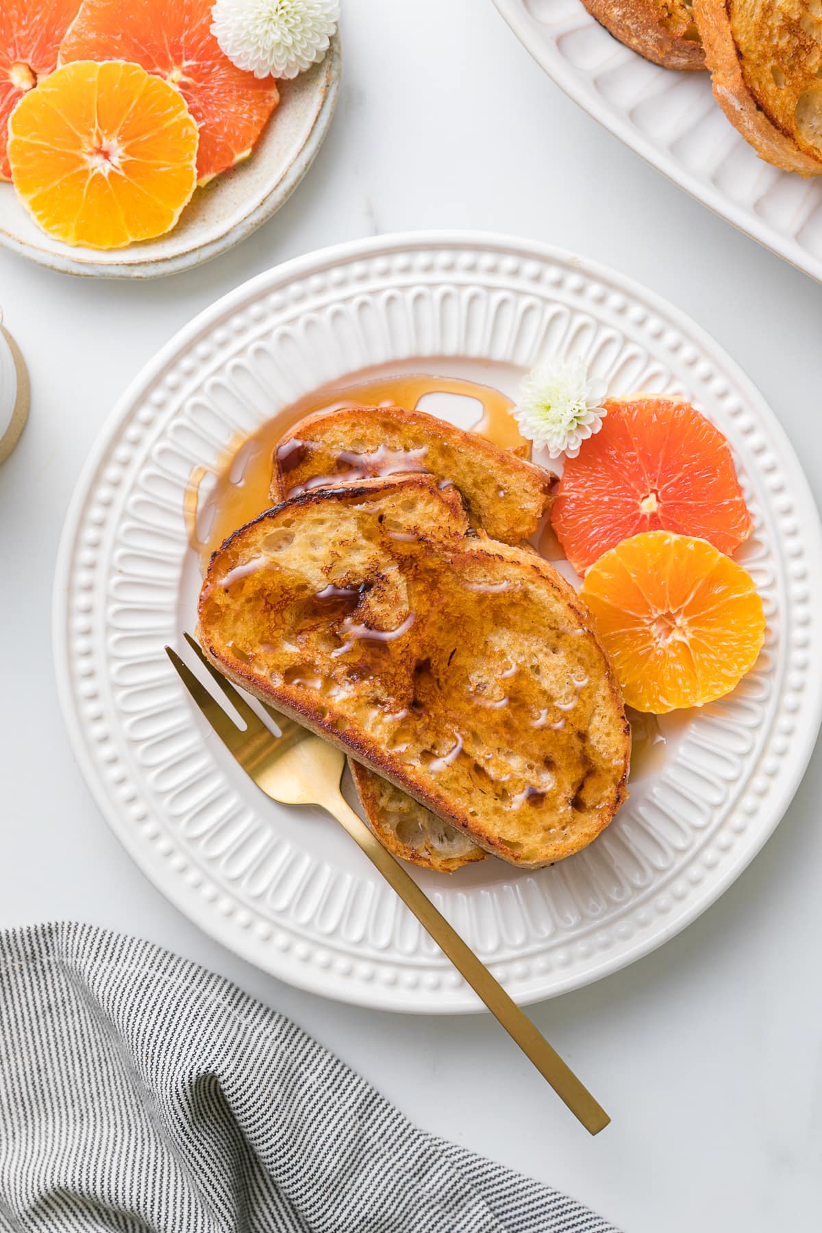 top down view of plated vegan orange french toast with maple syrup being poured over top.
