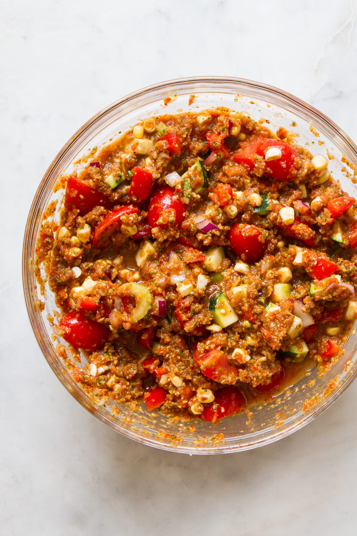 top down view of freshly made raw veggie chili in a glass mixing bowl.