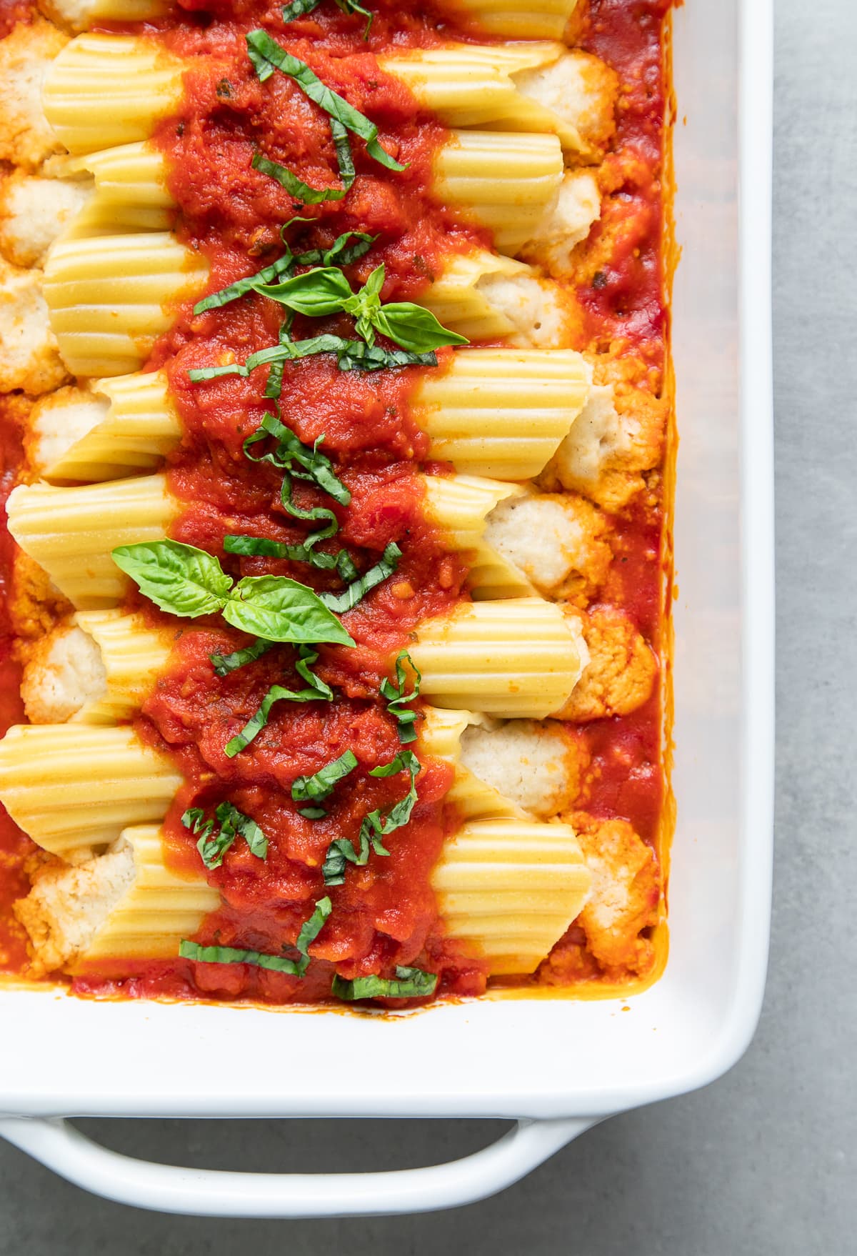 top down view of freshly baked vegan manicotti in a white baking dish.