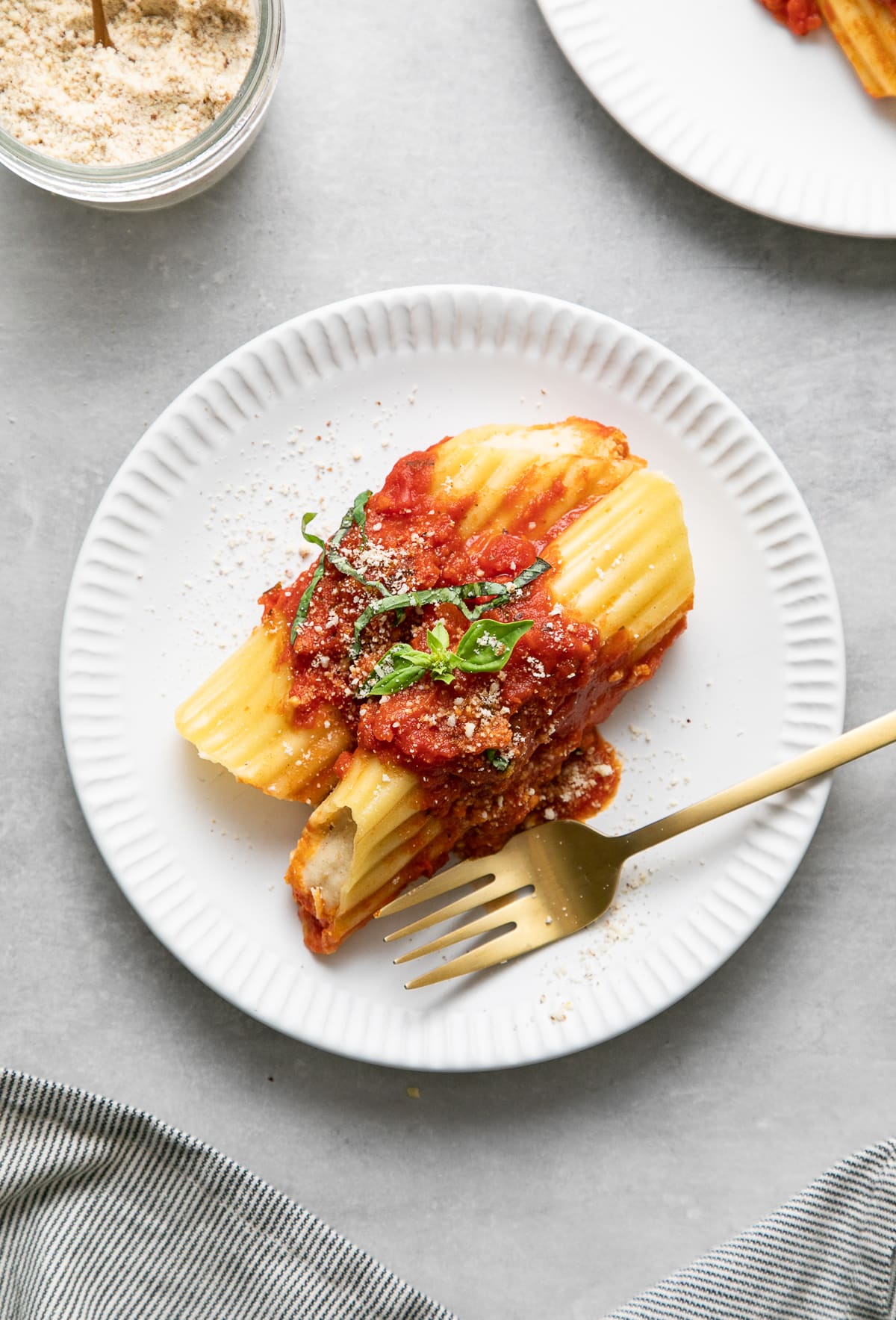 top down view of a serving of vegan manicotti on a small white plate with fork.