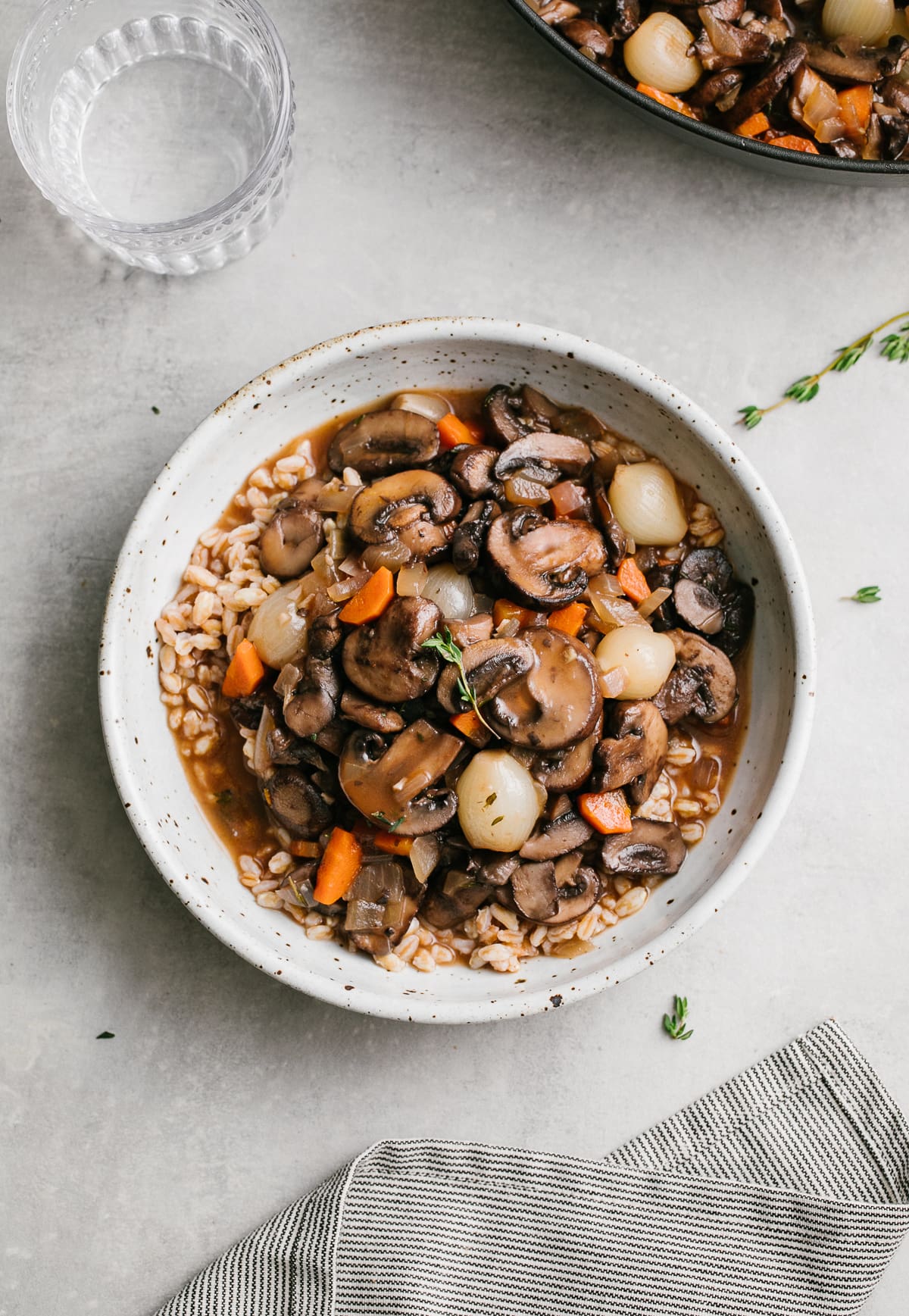 top down view of handmade bowl with a serving of mushroom bourguignon and farro with items surrounding.